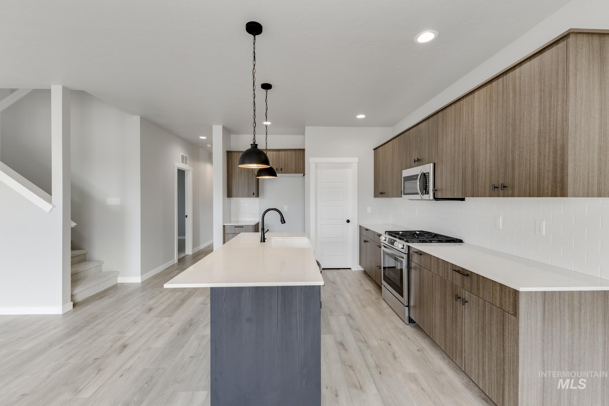Kitchen with a kitchen island with sink, tasteful backsplash, stainless steel appliances, modern cabinets, and recessed lighting