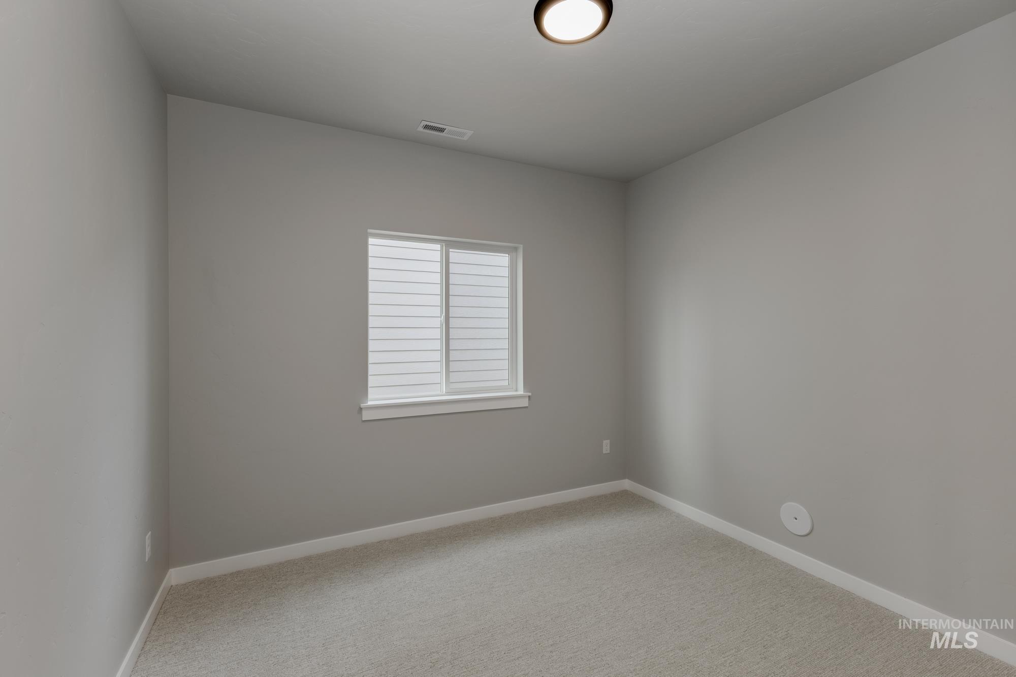 Spare room with light carpet and baseboards