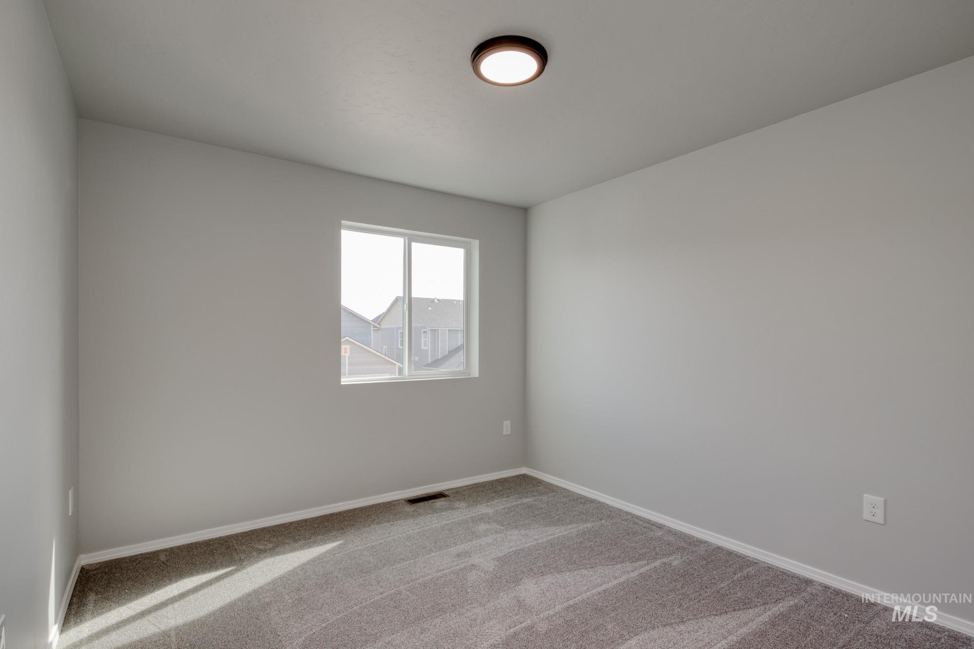 Carpeted spare room featuring baseboards