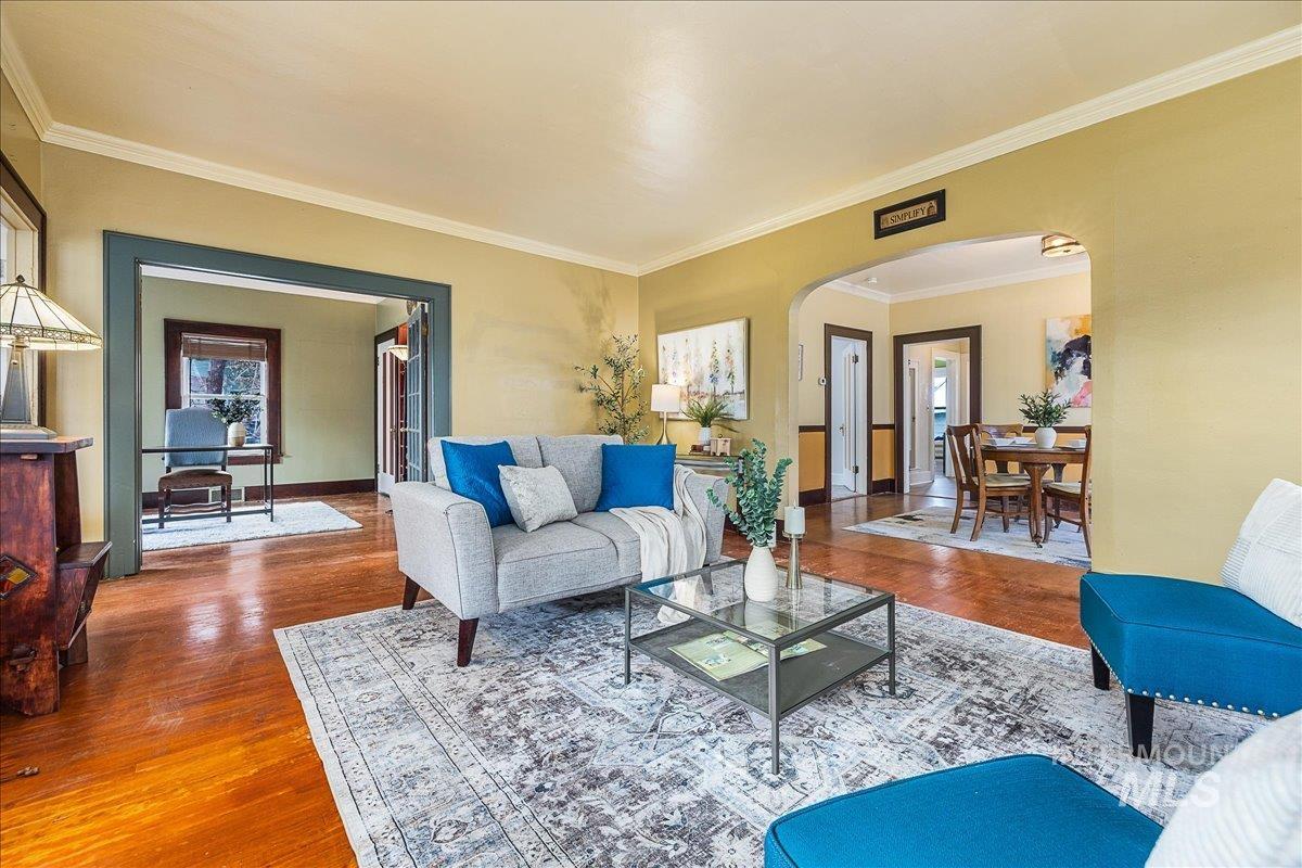 Living area featuring arched walkways, ornamental molding, and wood finished floors