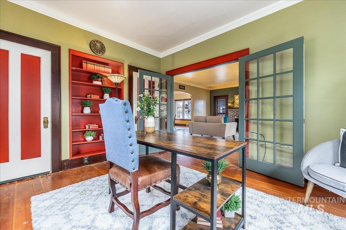 Home office with ornamental molding, wood finished floors, and built in features