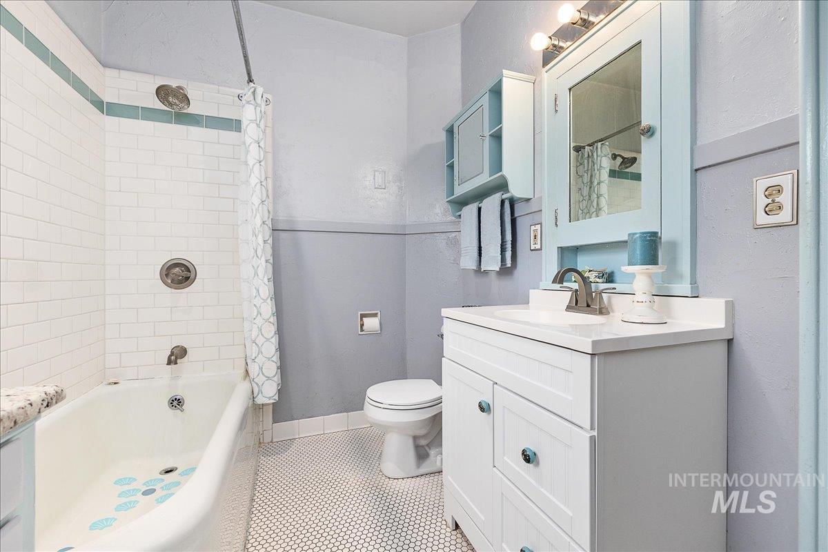 Full bath with vanity, shower / tub combo, a textured wall, and light tile patterned floors