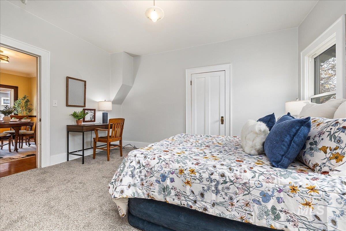 Carpeted bedroom featuring multiple windows and ornamental molding