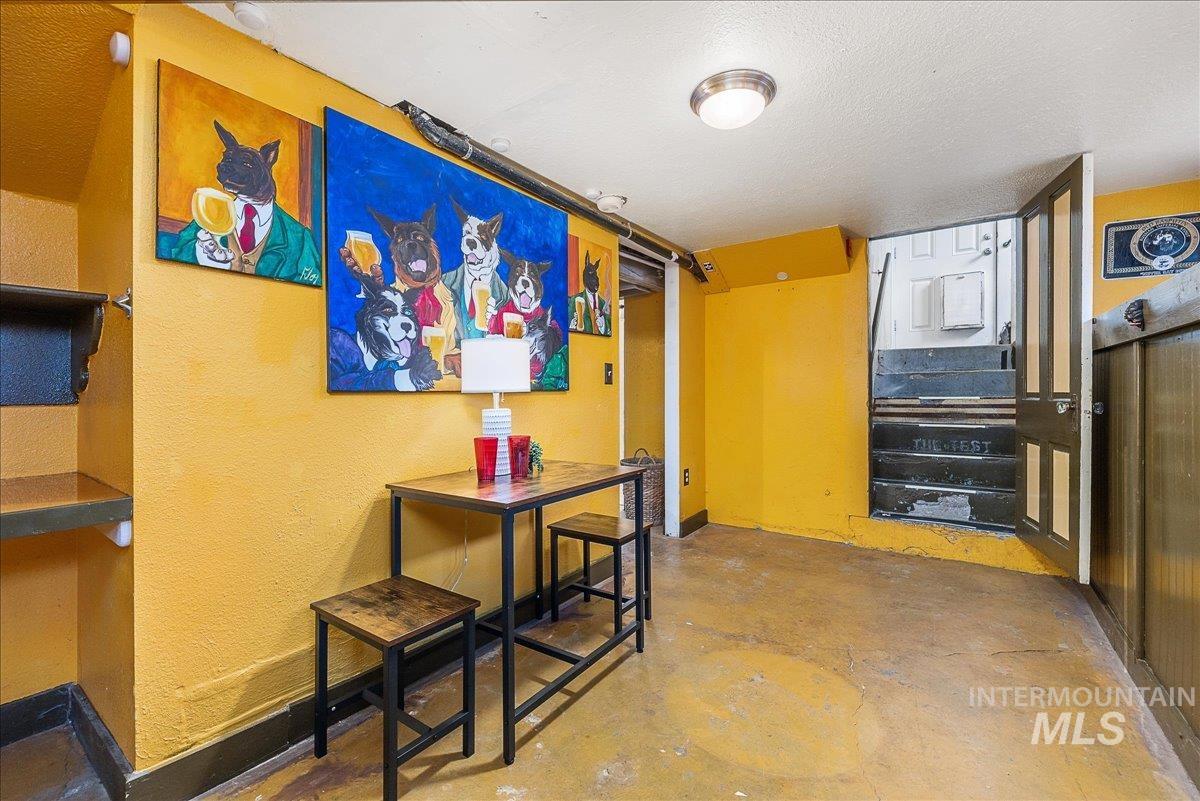 Corridor with concrete floors, a textured wall, stairway, and a textured ceiling