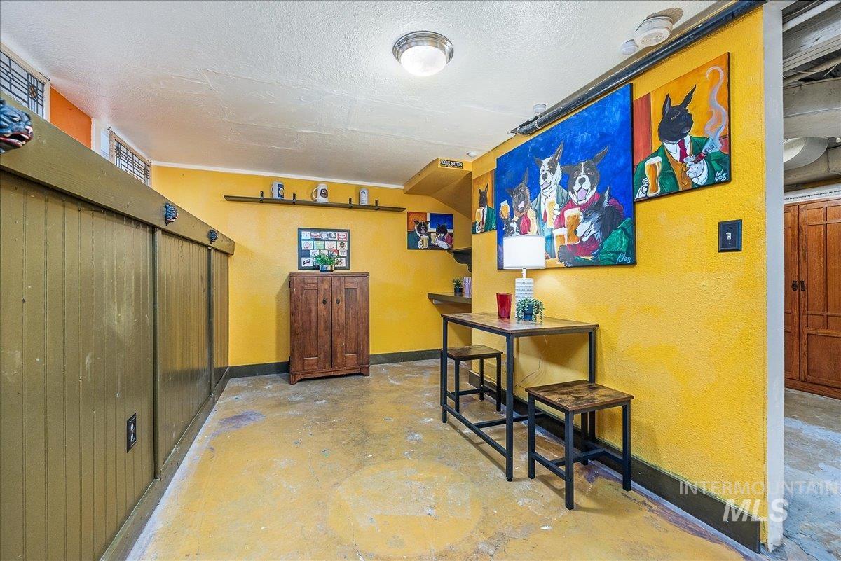 Bar area featuring concrete flooring, a textured ceiling, and a textured wall
