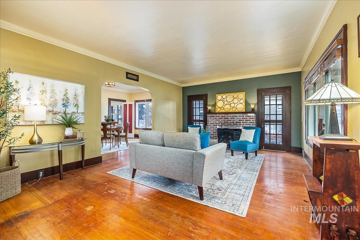 Living area featuring arched walkways, hardwood / wood-style flooring, ornamental molding, and a fireplace