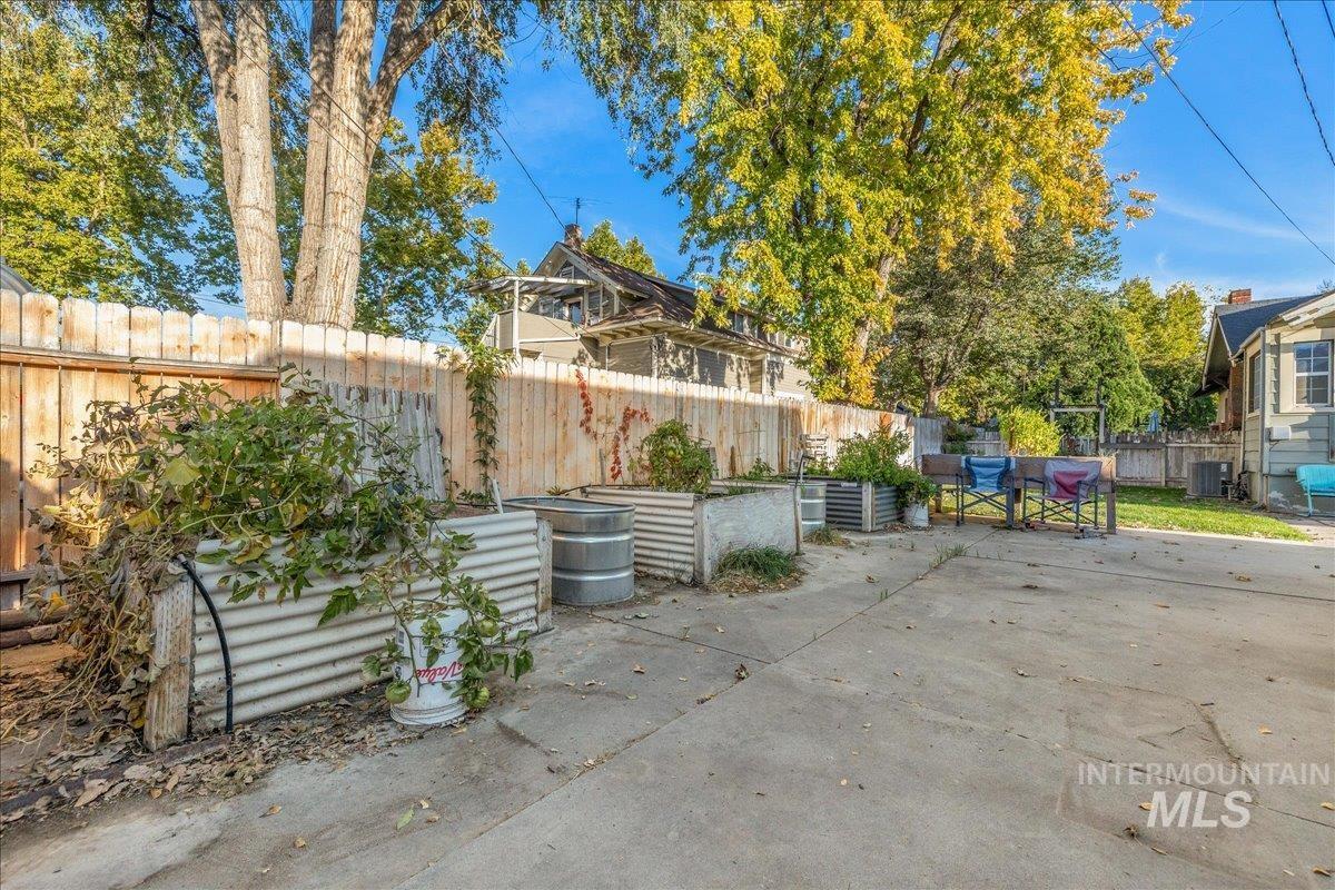Fenced backyard featuring a vegetable garden and a patio area