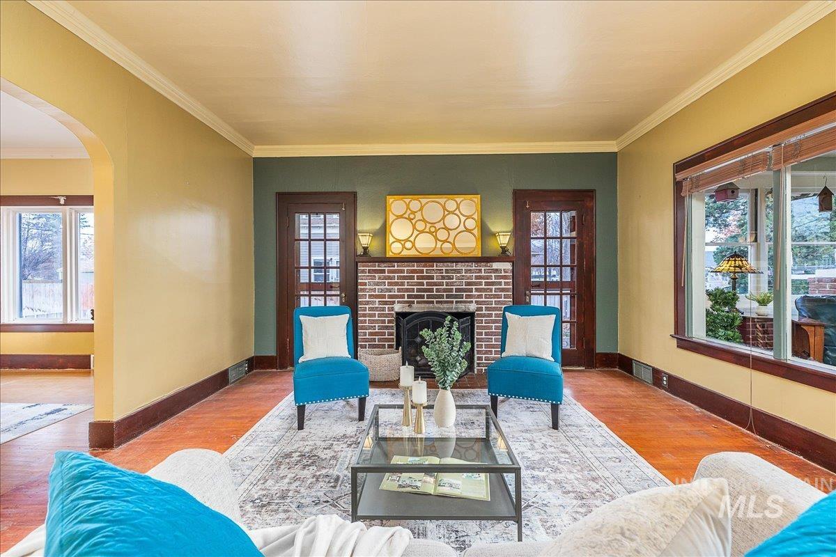 Living room featuring arched walkways, plenty of natural light, a brick fireplace, and crown molding