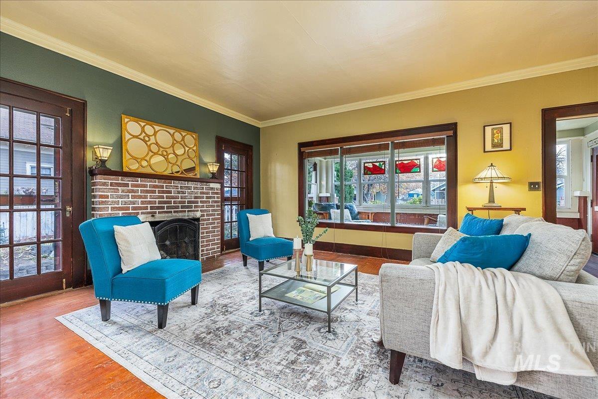 Living room with ornamental molding, wood finished floors, and a fireplace