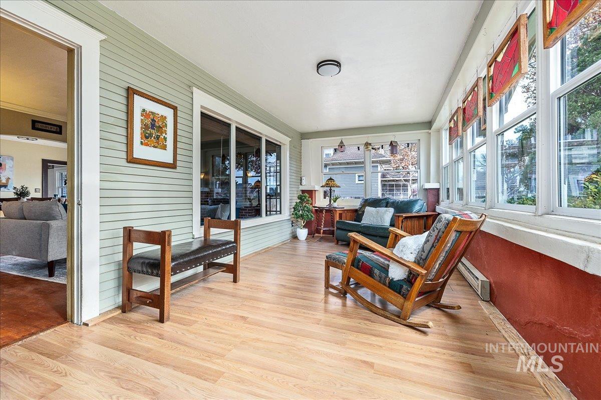 Sunroom with plenty of natural light, wood finished floors, wood walls, and a baseboard radiator