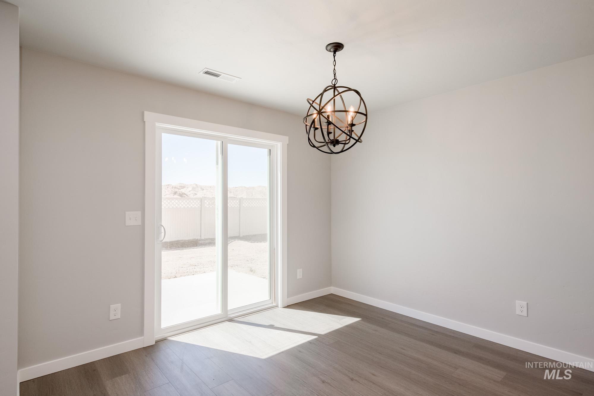 Spare room with wood finished floors and a chandelier