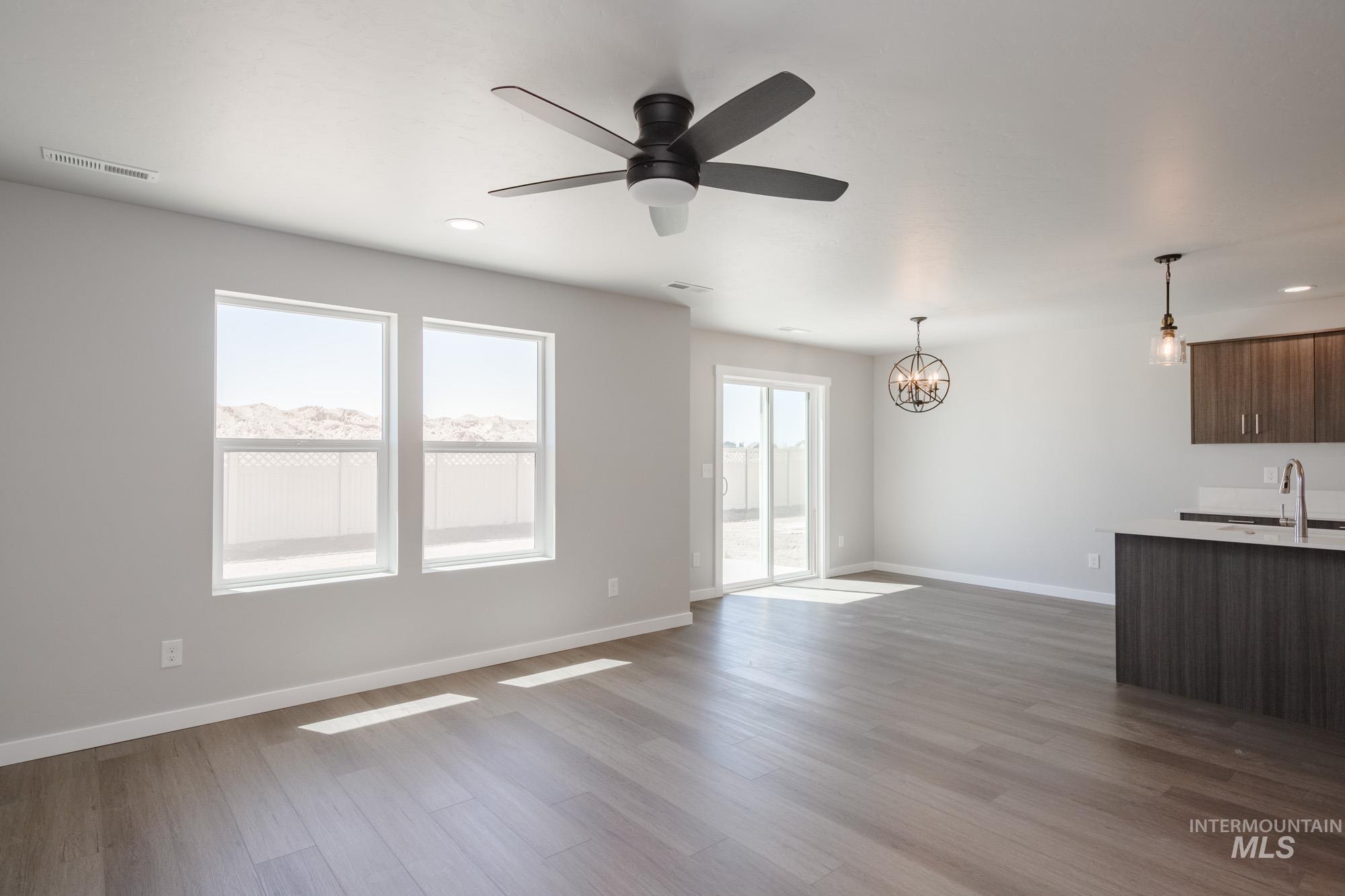 Unfurnished living room featuring light wood-style flooring, a chandelier, ceiling fan, and recessed lighting