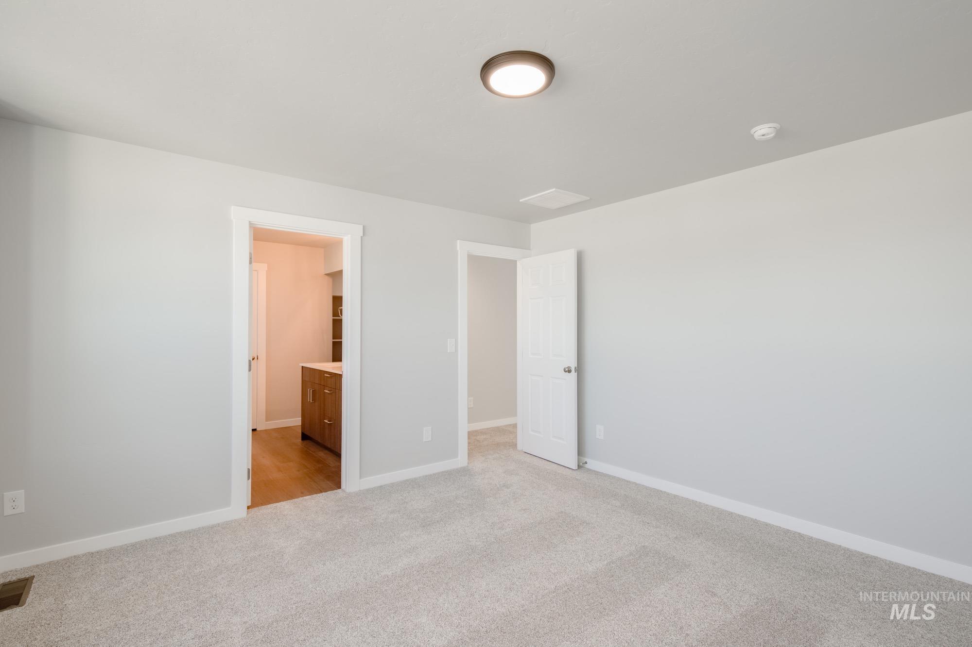 Unfurnished bedroom with light colored carpet and ensuite bath