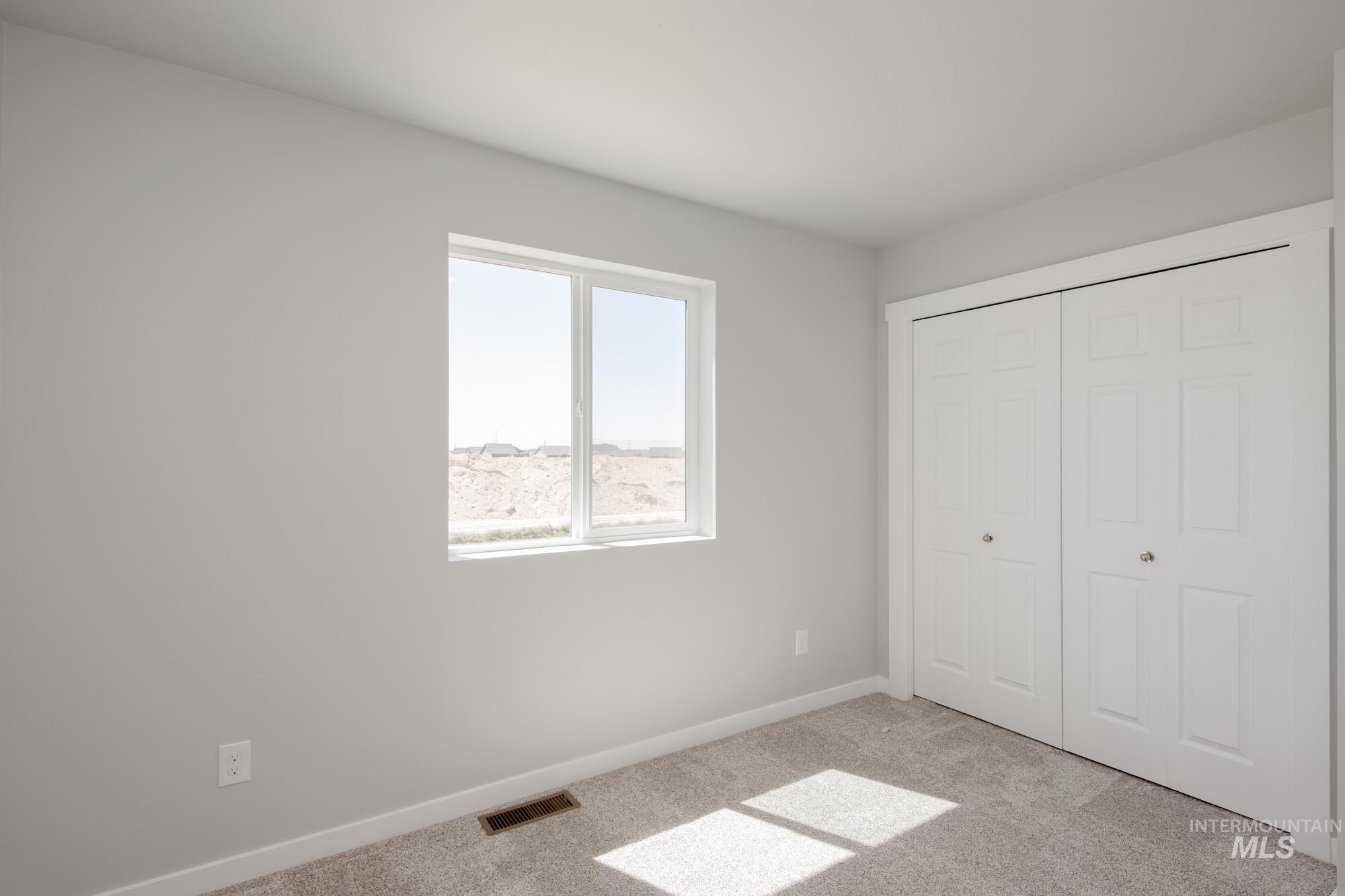 Unfurnished bedroom featuring light carpet and a closet