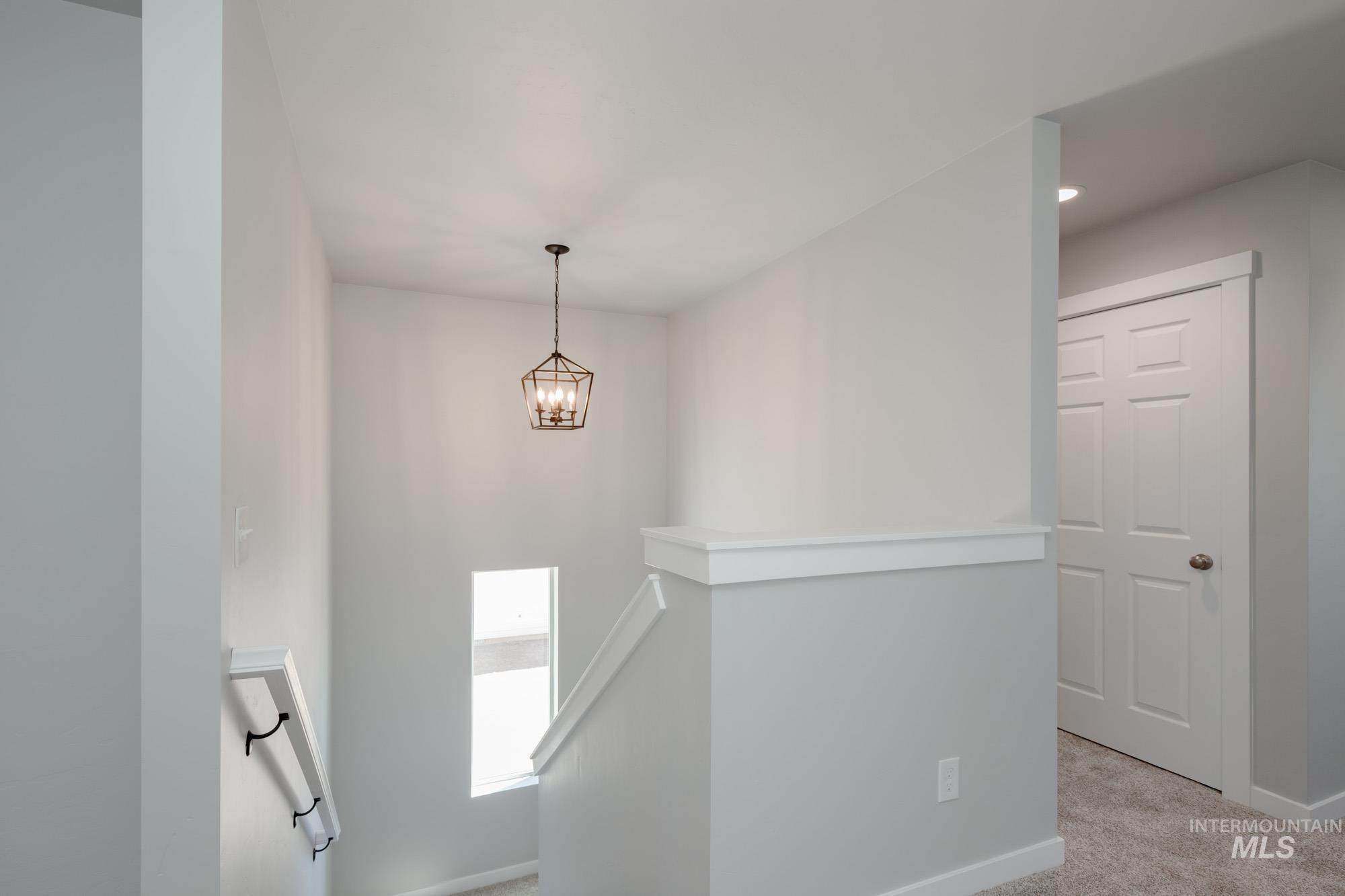 Corridor with an upstairs landing, carpet, a chandelier, and recessed lighting