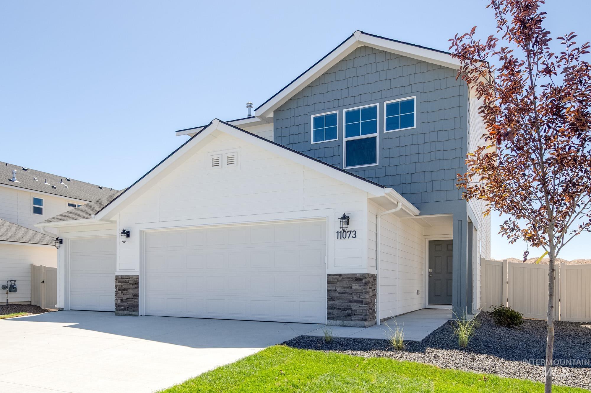 View of front facade featuring stone siding, concrete driveway, a gate, and an attached garage