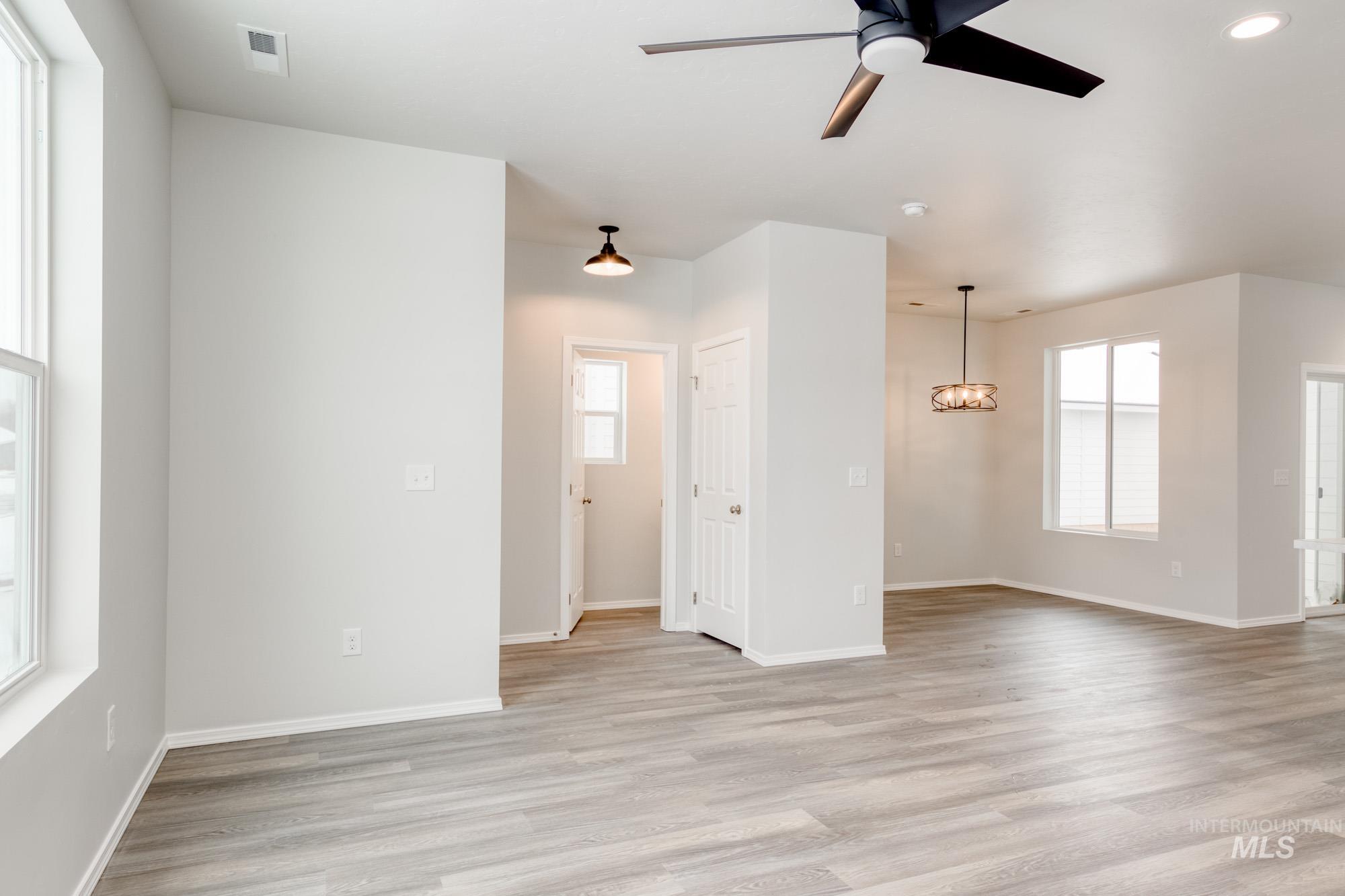 Unfurnished living room featuring plenty of natural light, a ceiling fan, and light wood-type flooring
