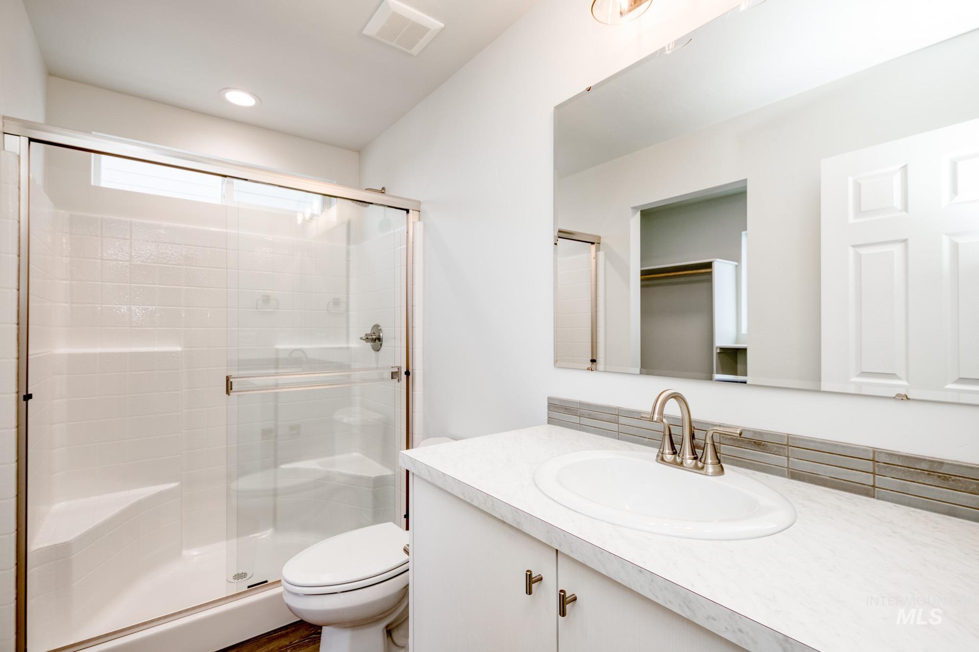Bathroom with a stall shower, vanity, and recessed lighting