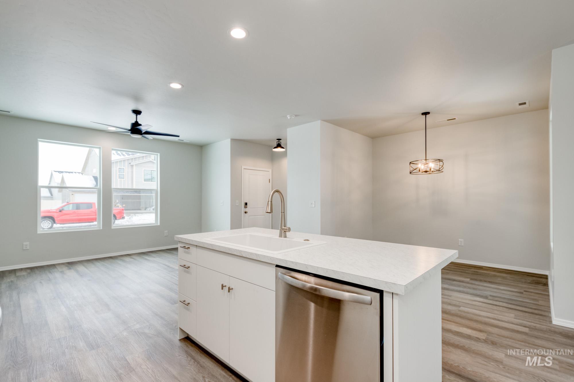 Kitchen featuring light countertops, dishwasher, white cabinets, ceiling fan, and light wood-style flooring