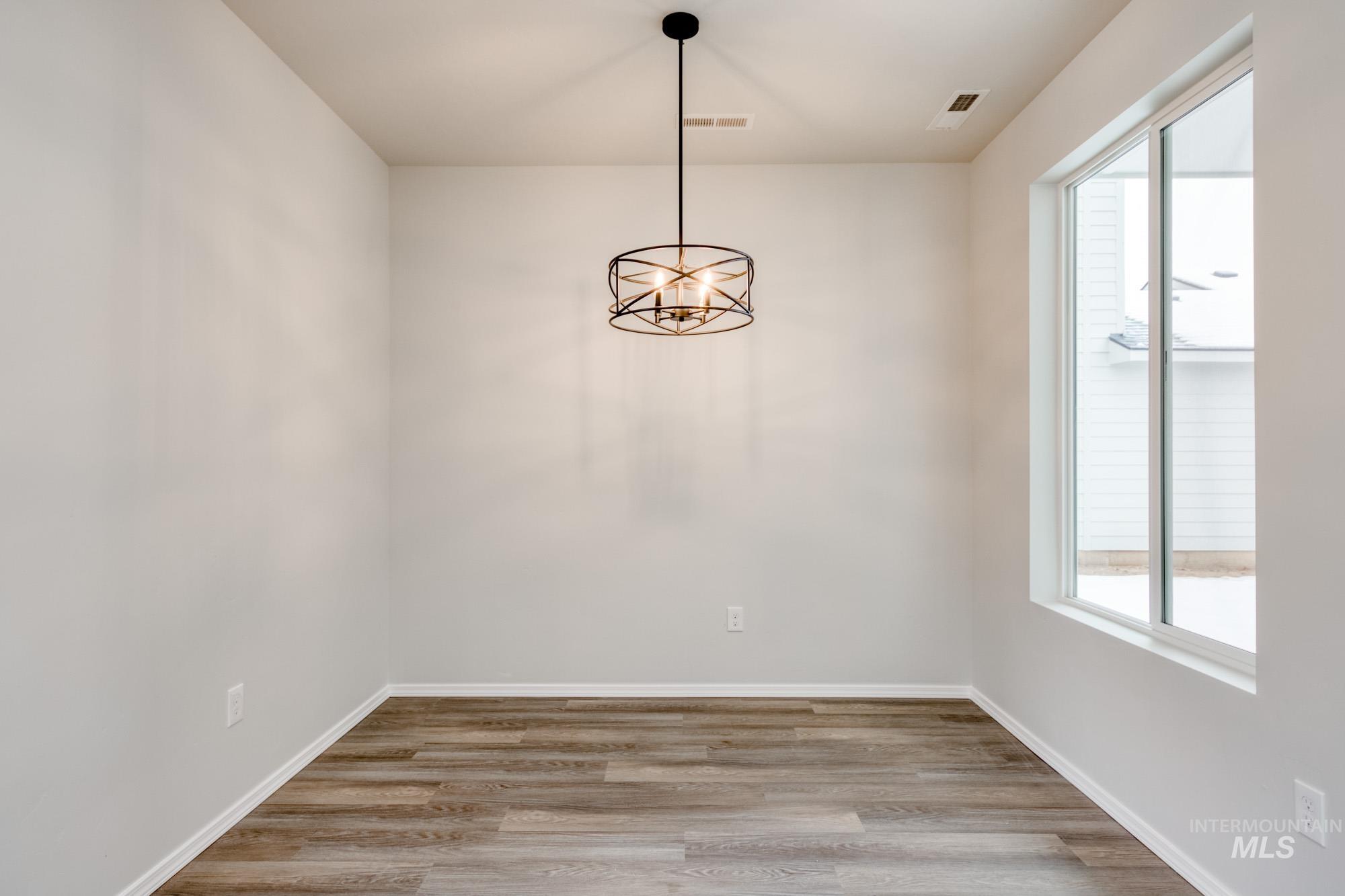 Unfurnished dining area with plenty of natural light, light wood finished floors, and a chandelier