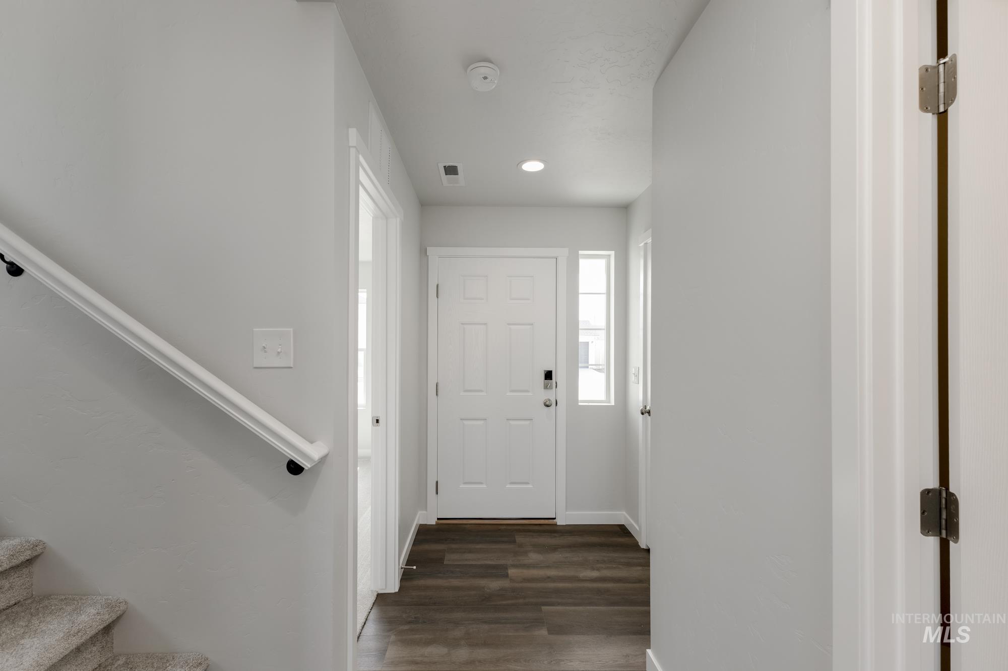 Foyer entrance with stairs, dark wood finished floors, and recessed lighting