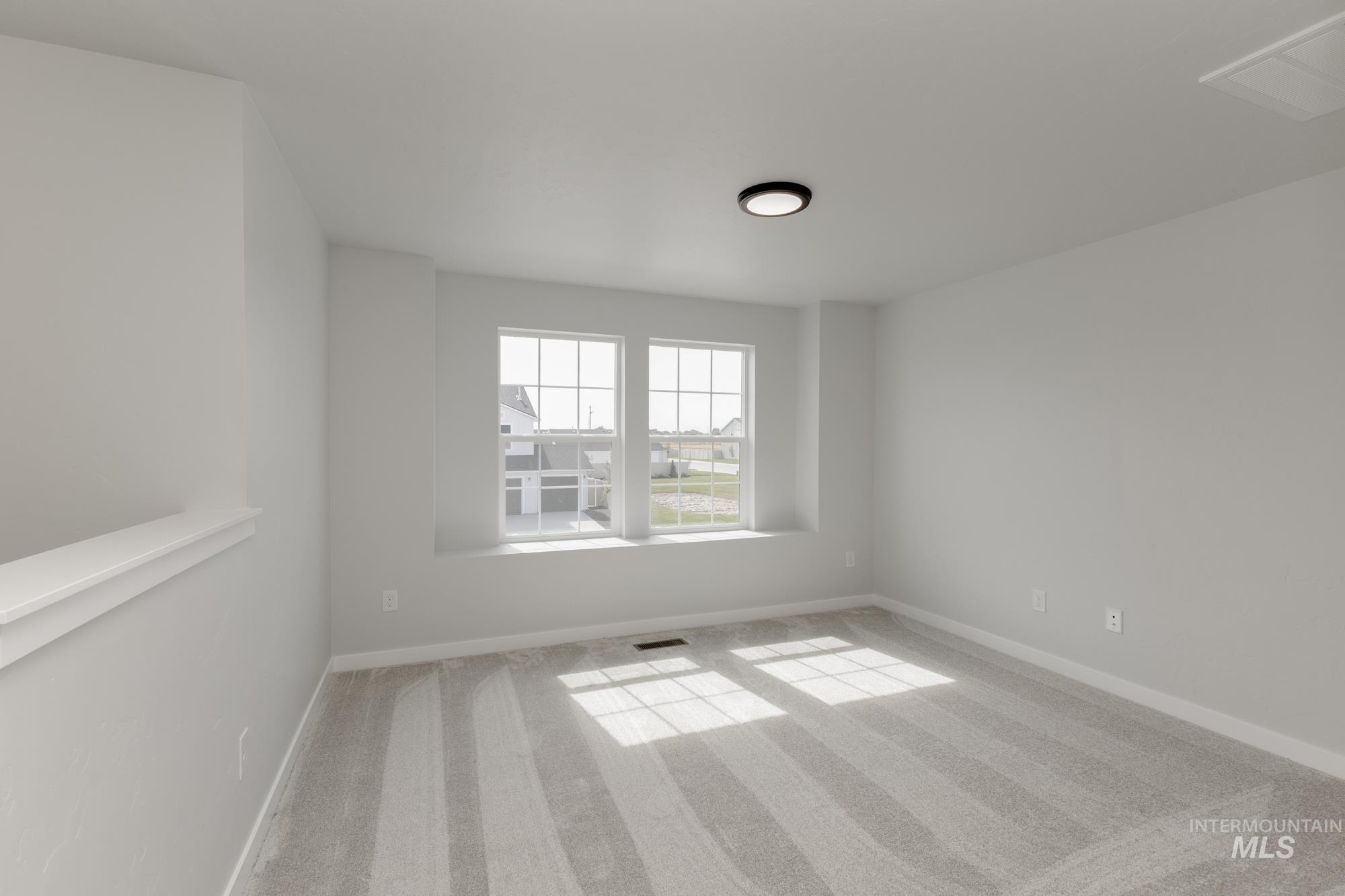 Empty room featuring light colored carpet and baseboards