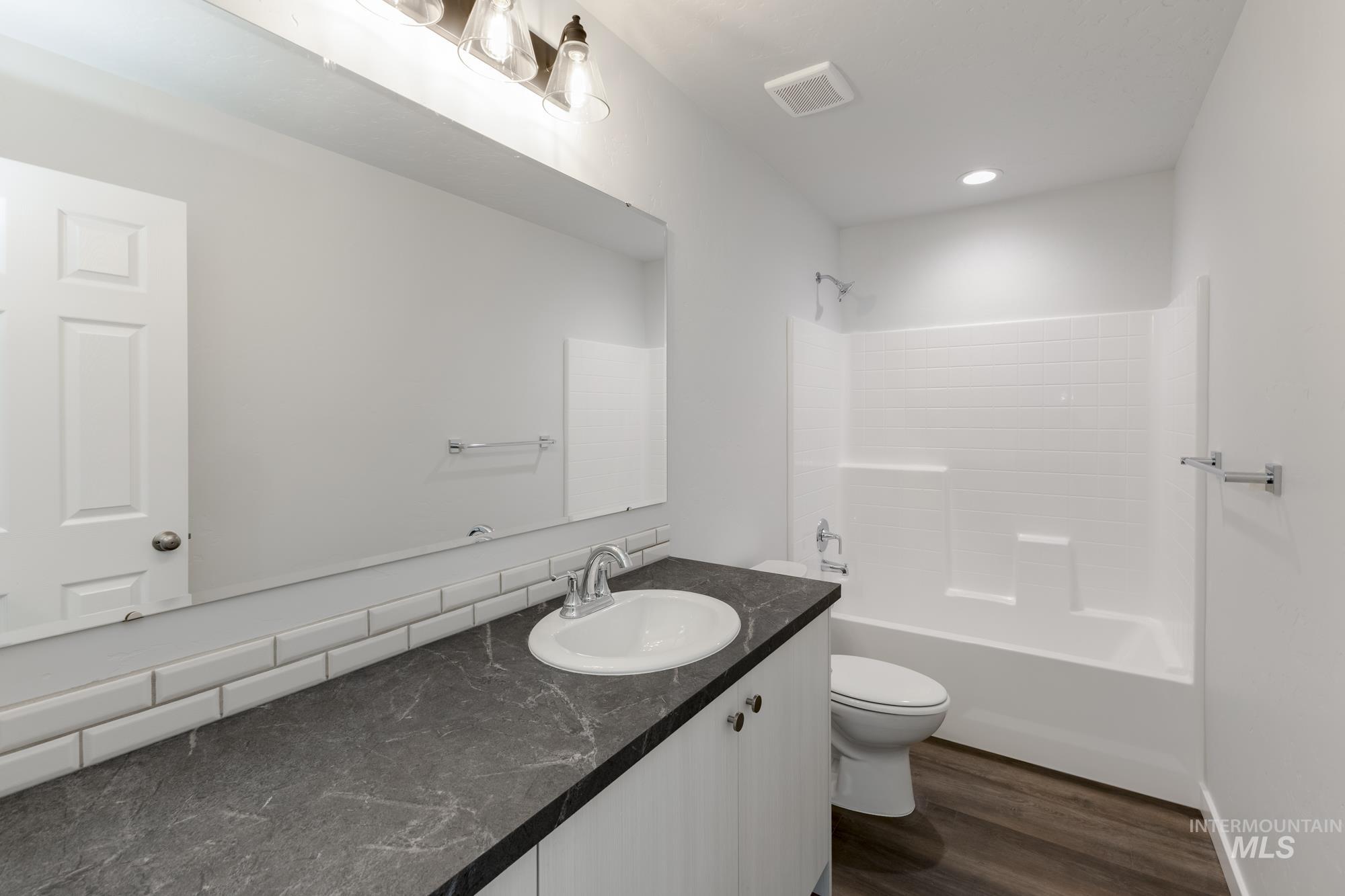 Full bath with vanity,  shower combination, dark wood-style flooring, and recessed lighting
