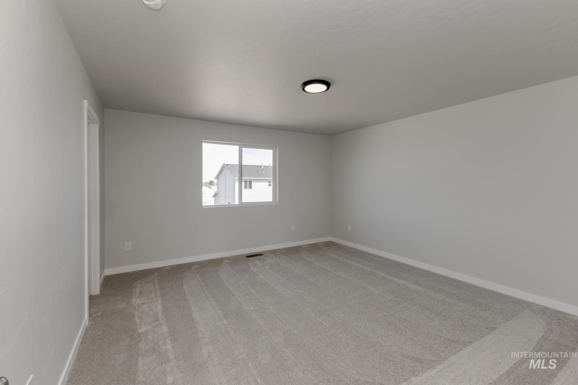 Empty room featuring light carpet and baseboards