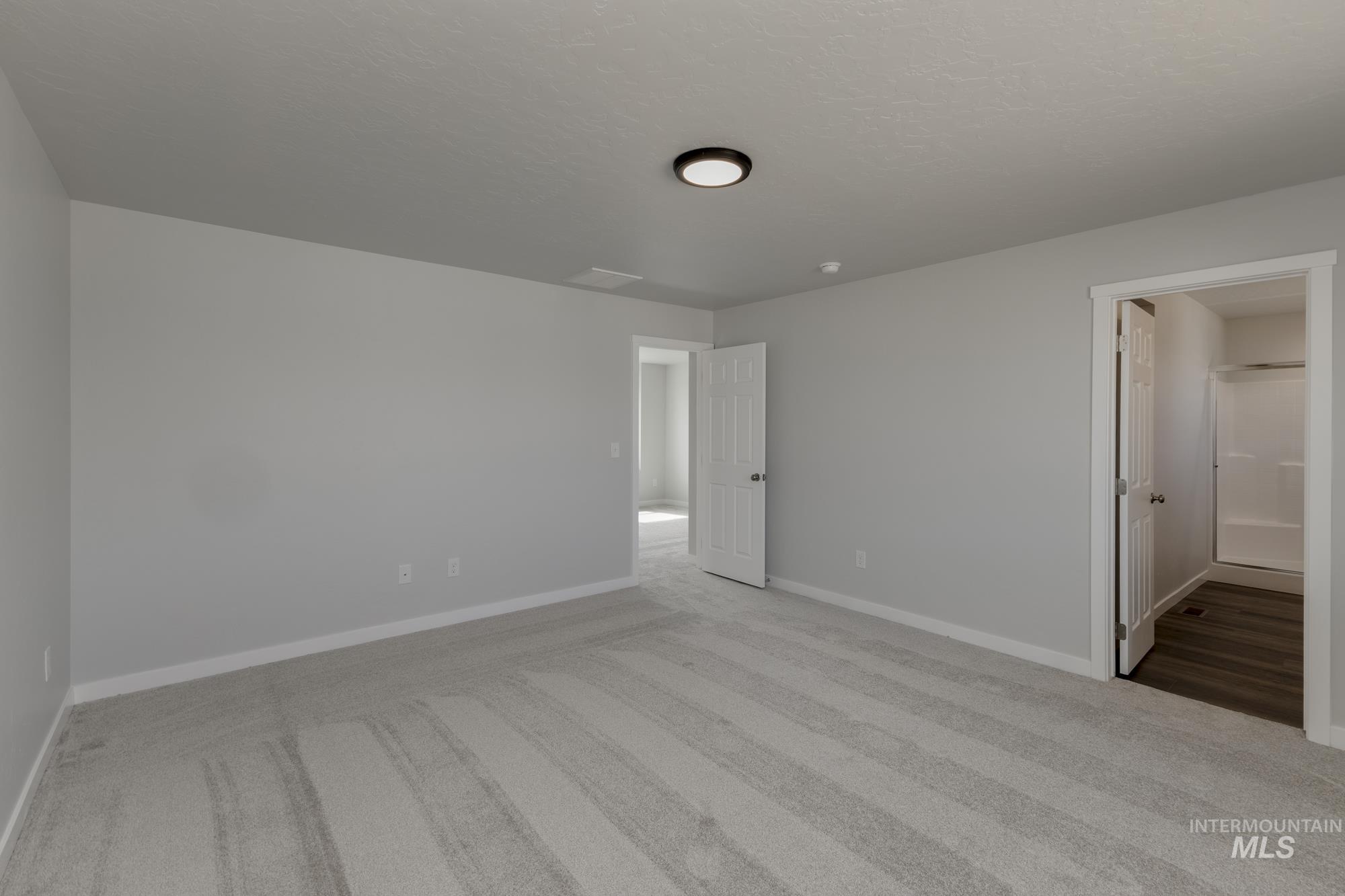 Unfurnished bedroom with light carpet and connected bathroom