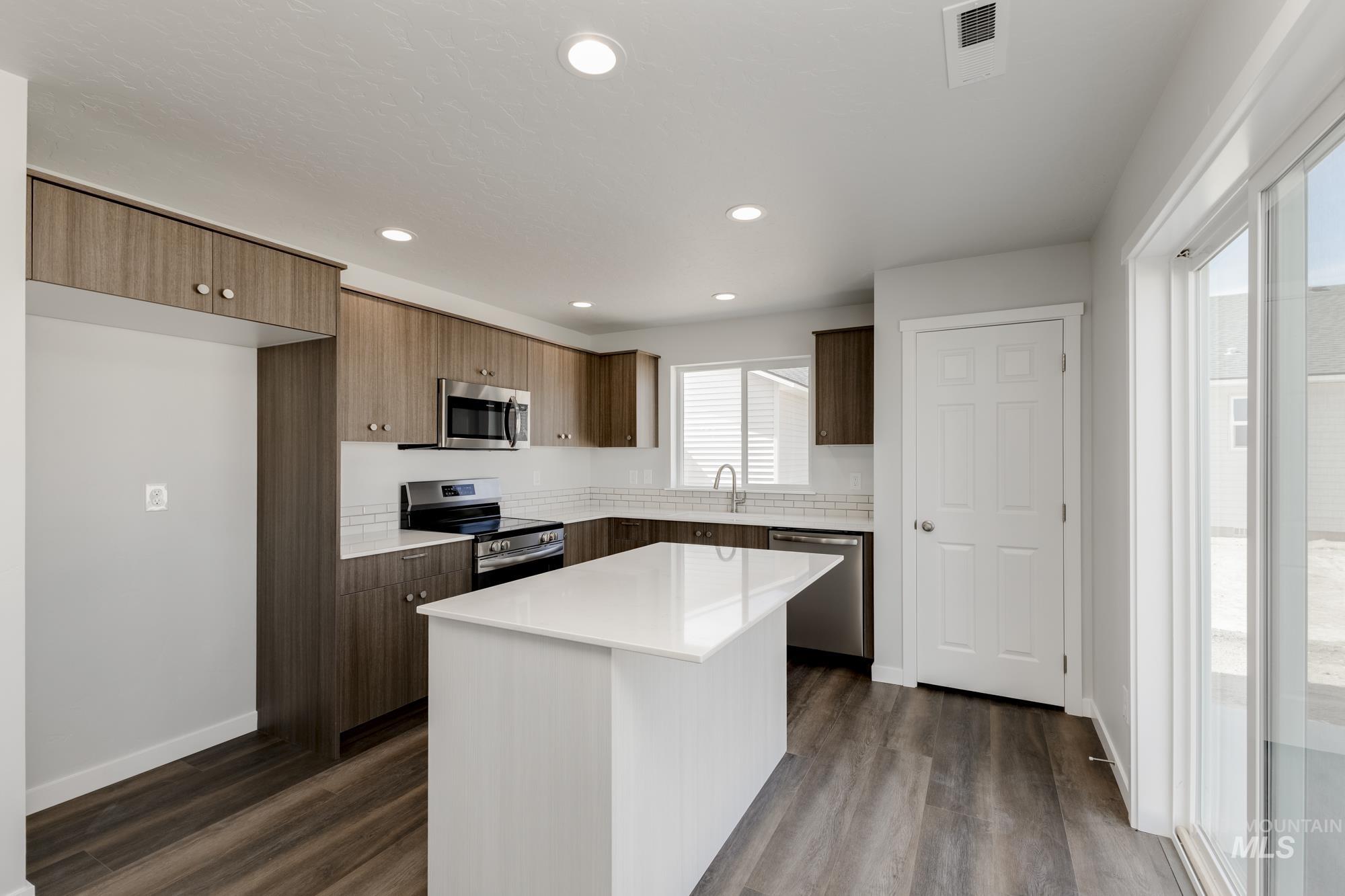 Kitchen with stainless steel appliances, modern cabinets, dark wood-style floors, recessed lighting, and a kitchen island
