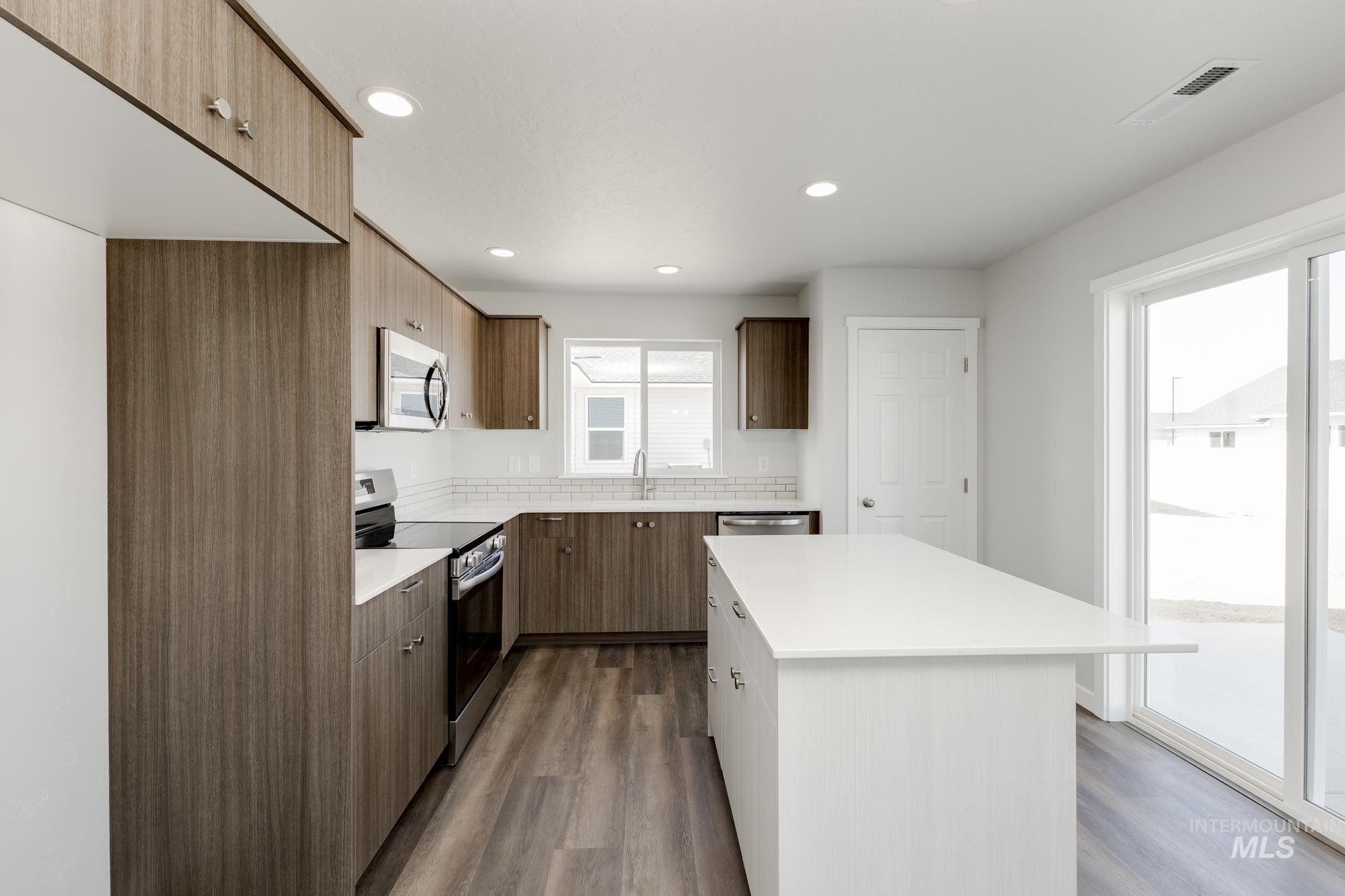 Kitchen featuring stainless steel appliances, dark wood finished floors, recessed lighting, a kitchen island, and modern cabinets