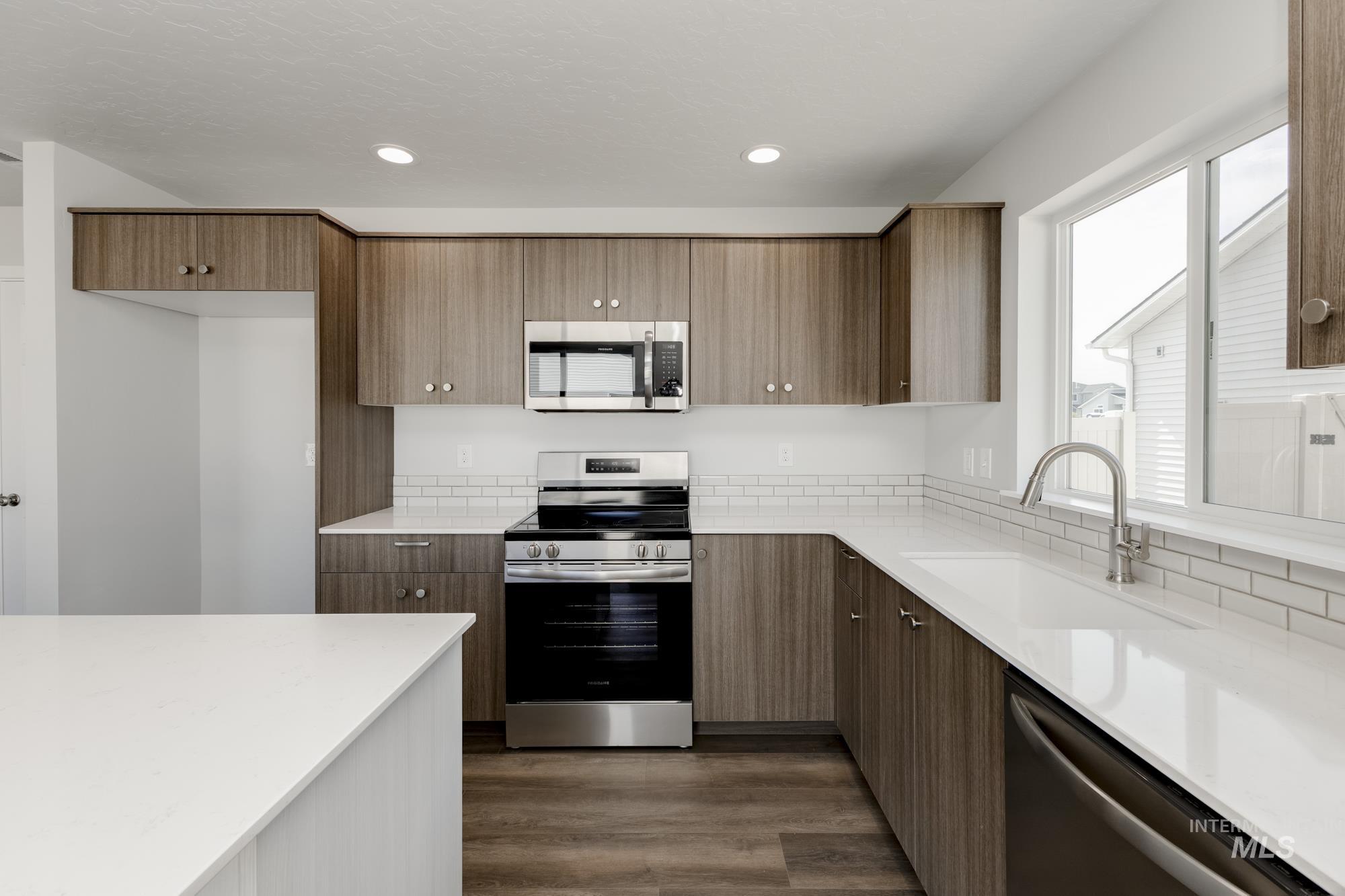 Kitchen with appliances with stainless steel finishes, light stone countertops, dark wood-style floors, modern cabinets, and recessed lighting