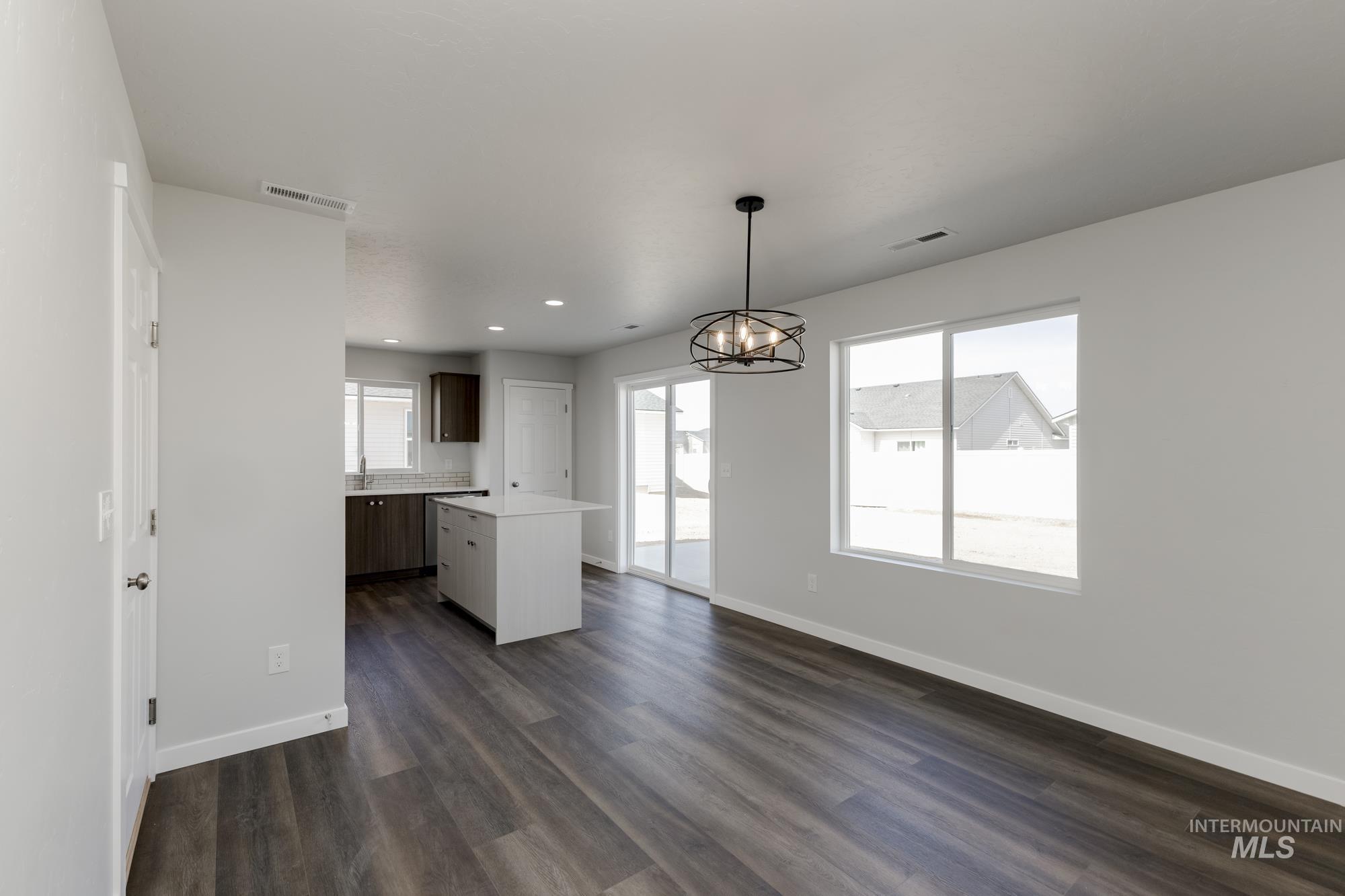 Kitchen featuring light countertops, decorative light fixtures, a center island, dark wood finished floors, and a chandelier