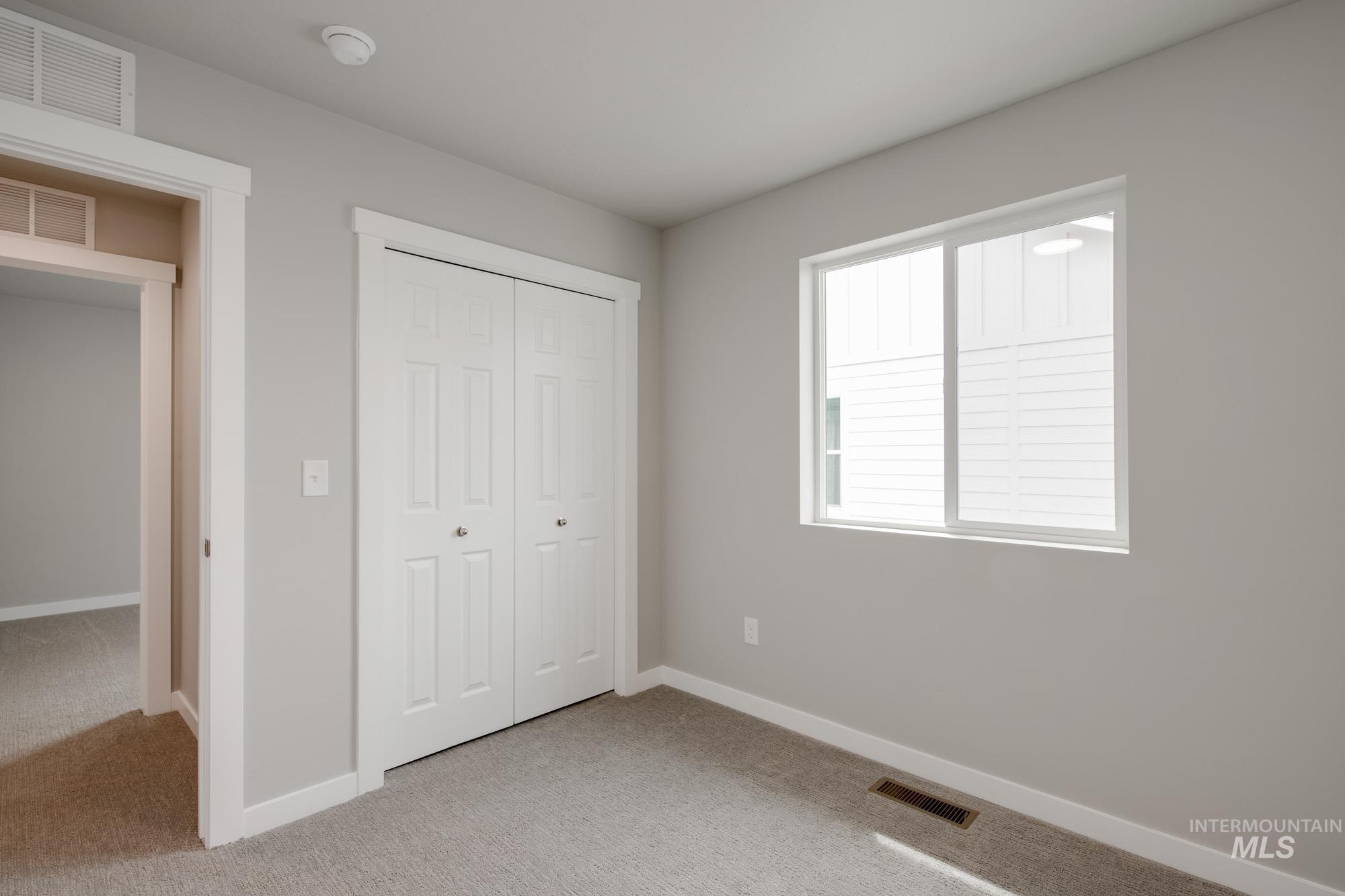 Unfurnished bedroom with light carpet and a closet