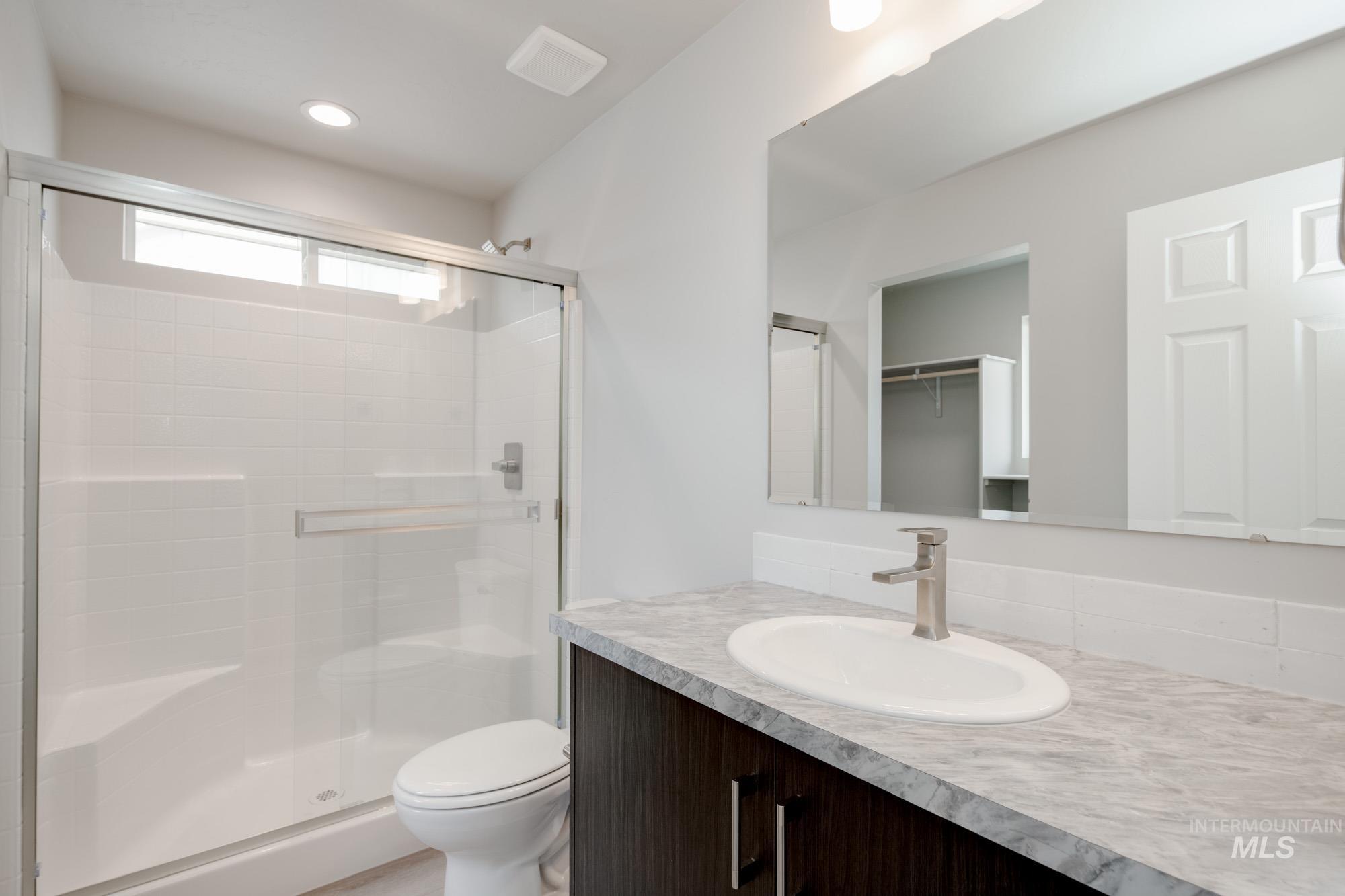 Full bath with a stall shower, vanity, a spacious closet, and recessed lighting