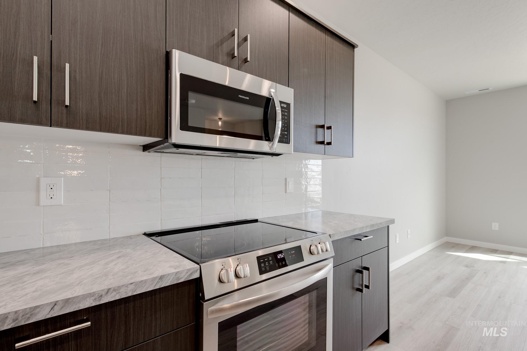 Kitchen with appliances with stainless steel finishes, light countertops, modern cabinets, and backsplash