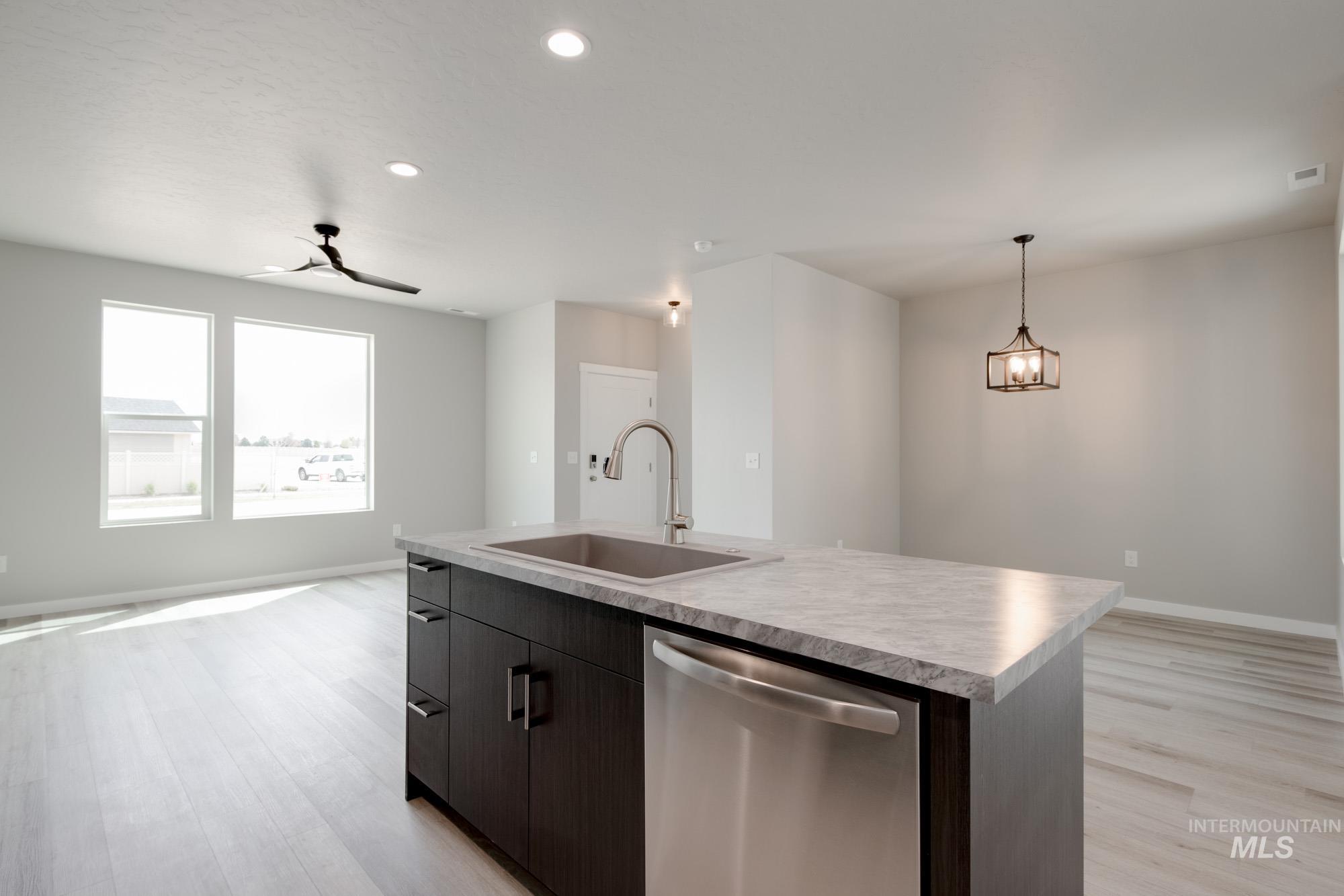 Kitchen featuring dishwasher, open floor plan, light countertops, light wood-style floors, and recessed lighting