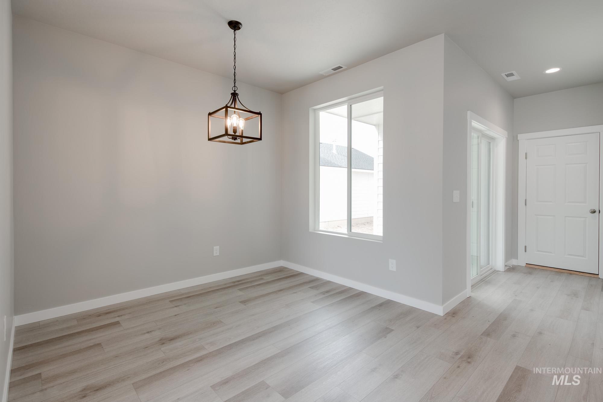 Unfurnished dining area with light wood-type flooring and a chandelier