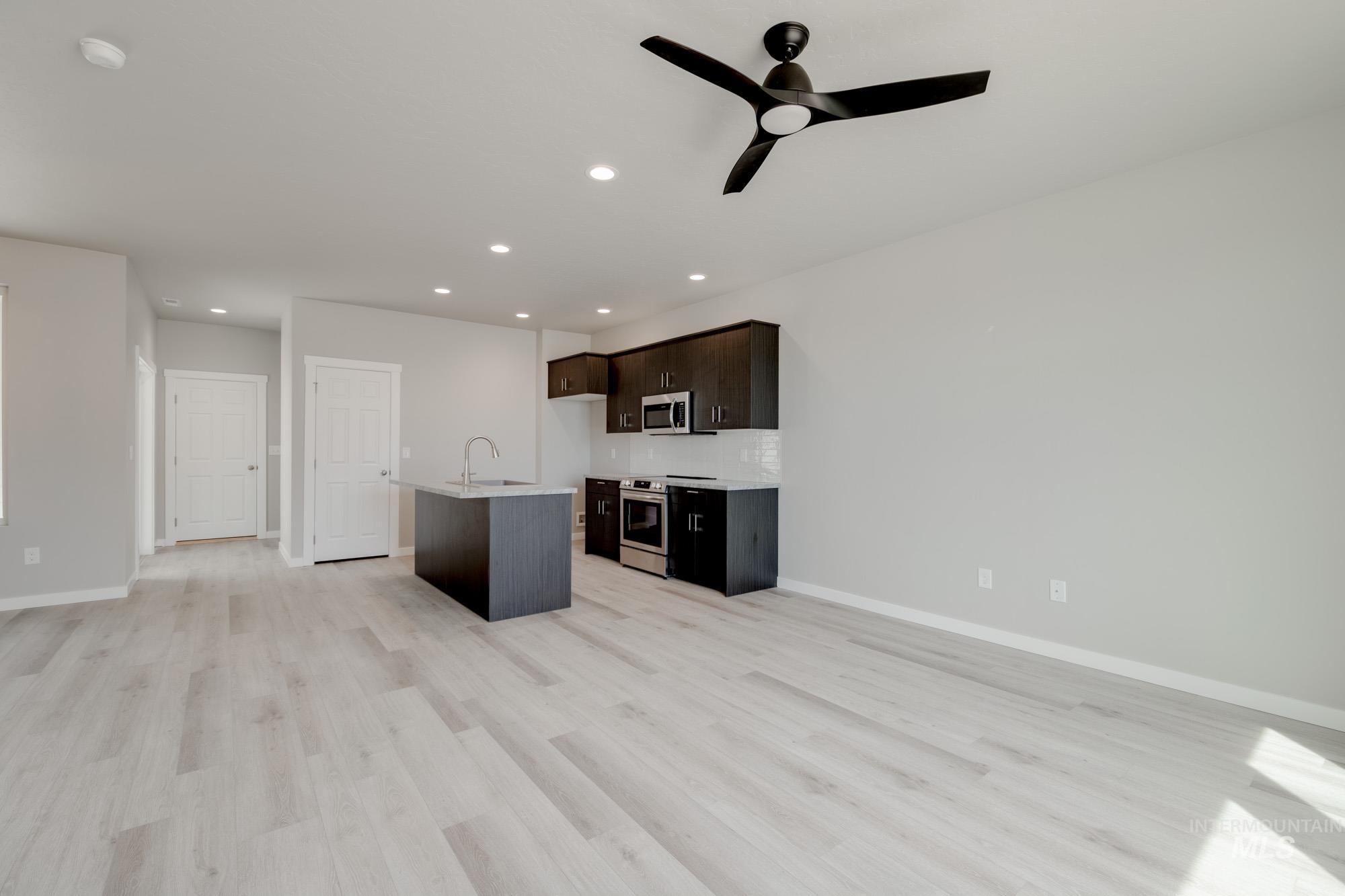 Kitchen featuring open floor plan, a kitchen island with sink, appliances with stainless steel finishes, light wood-type flooring, and recessed lighting
