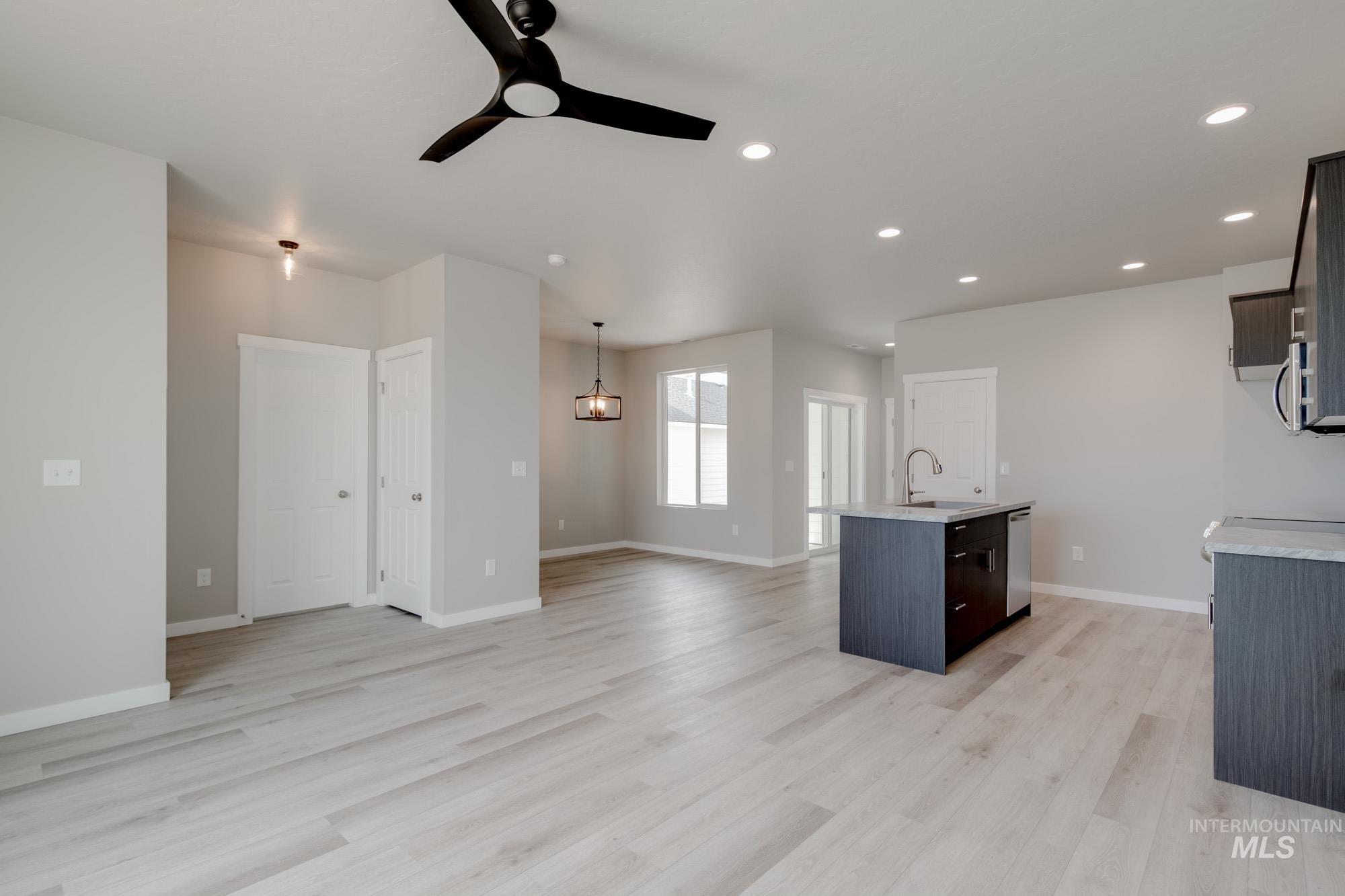 Unfurnished living room featuring light wood-type flooring, a ceiling fan, recessed lighting, and a chandelier