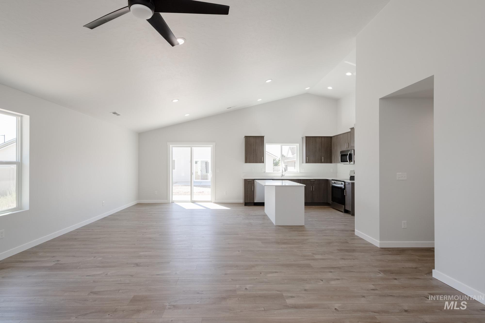 Unfurnished living room with light wood-style floors, high vaulted ceiling, ceiling fan, and recessed lighting