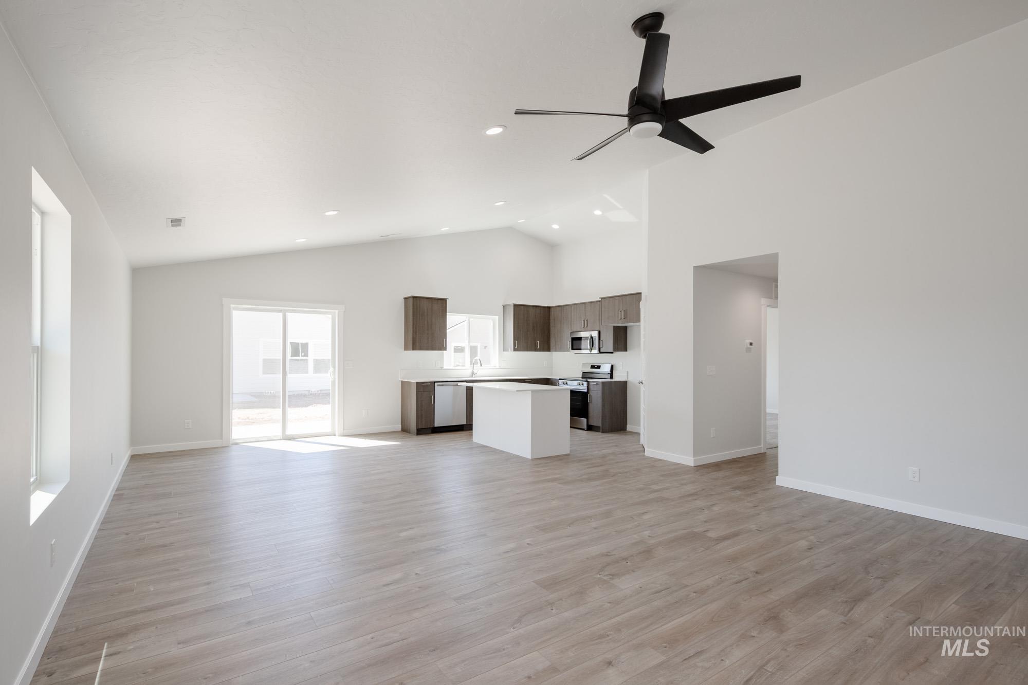 Unfurnished living room with high vaulted ceiling, light wood-type flooring, recessed lighting, and a ceiling fan