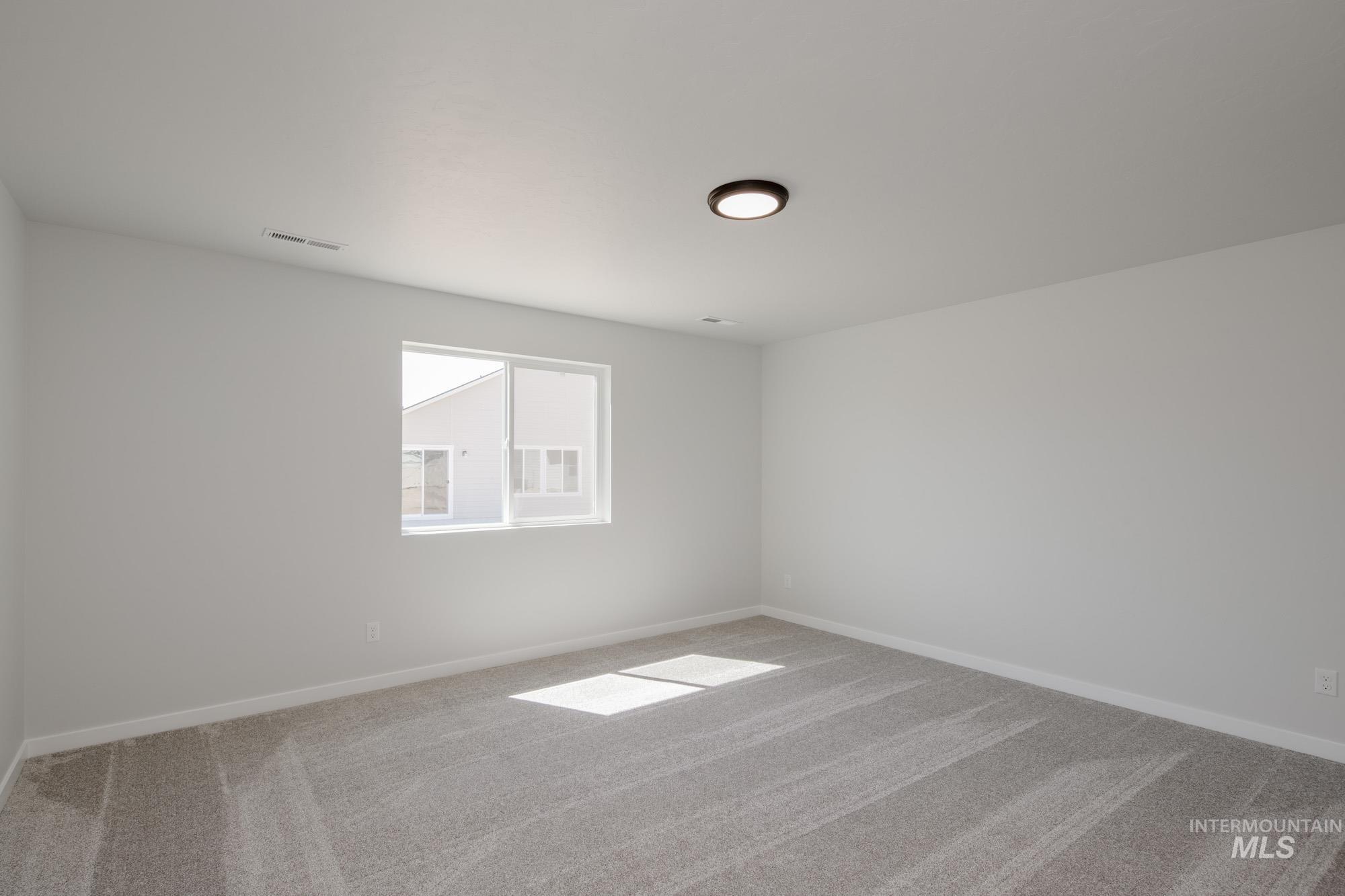 Empty room featuring light colored carpet and baseboards