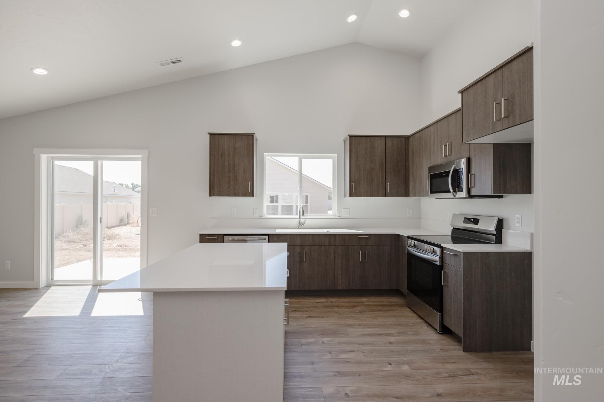 Kitchen featuring stainless steel appliances, modern cabinets, light wood-type flooring, recessed lighting, and dark brown cabinets