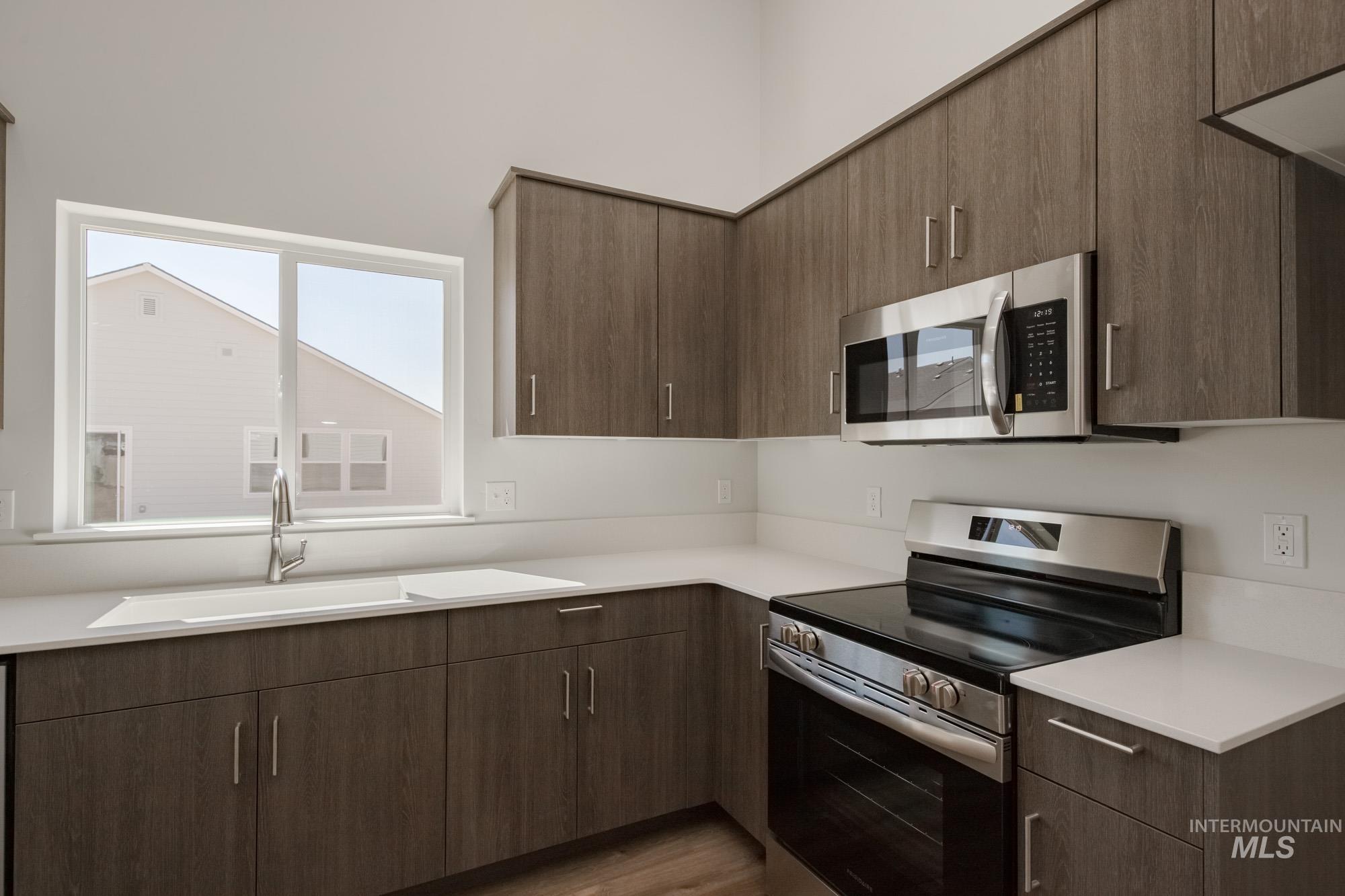 Kitchen featuring stainless steel appliances, modern cabinets, and dark wood-style flooring
