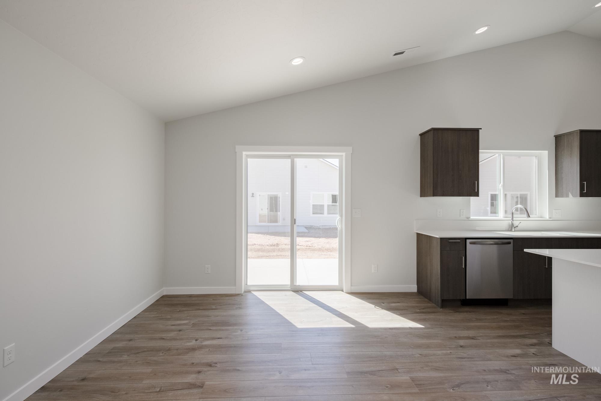 Kitchen with vaulted ceiling, dark brown cabinets, recessed lighting, dark wood finished floors, and stainless steel dishwasher