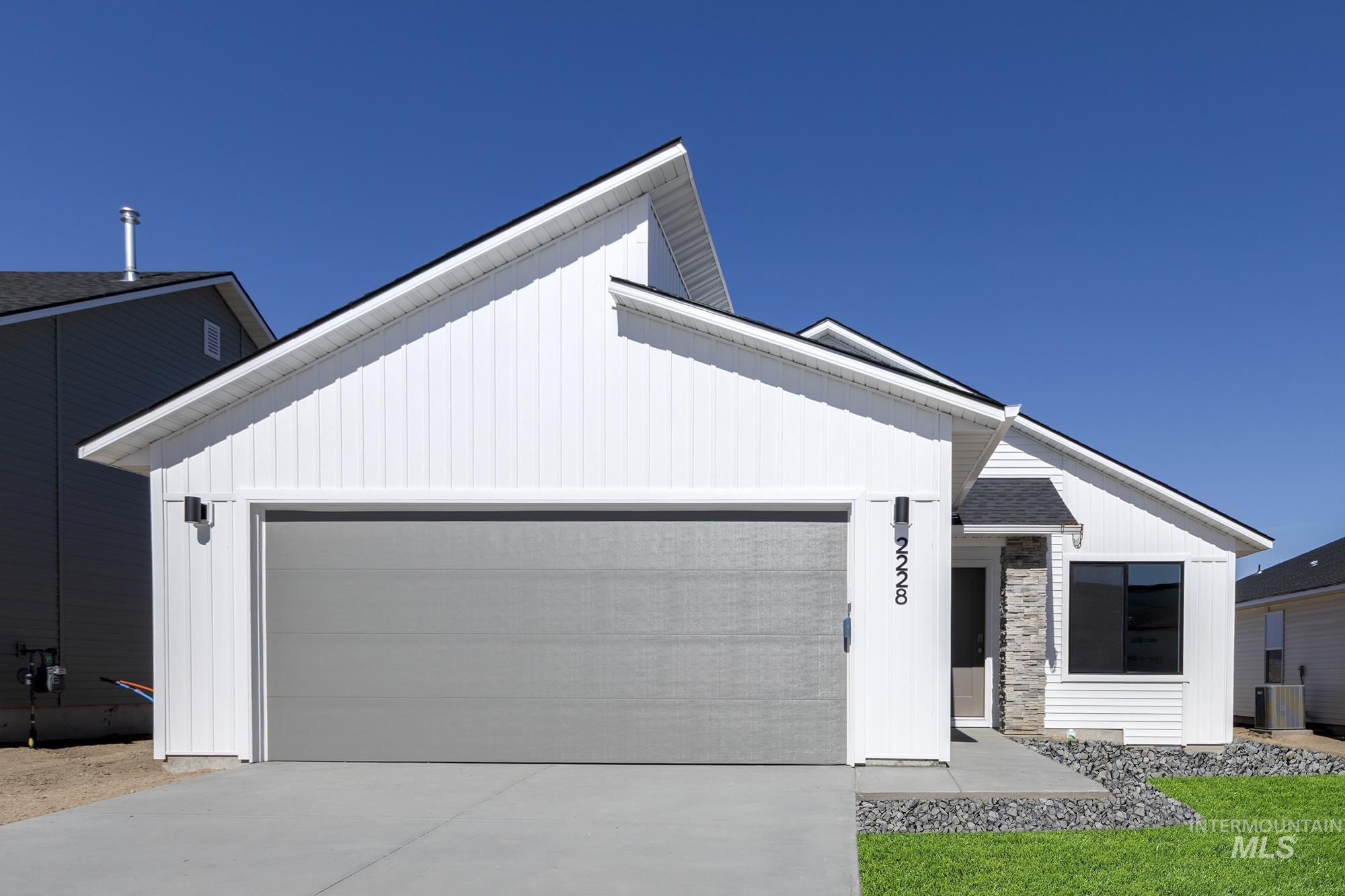 Modern farmhouse with a garage, concrete driveway, and board and batten siding