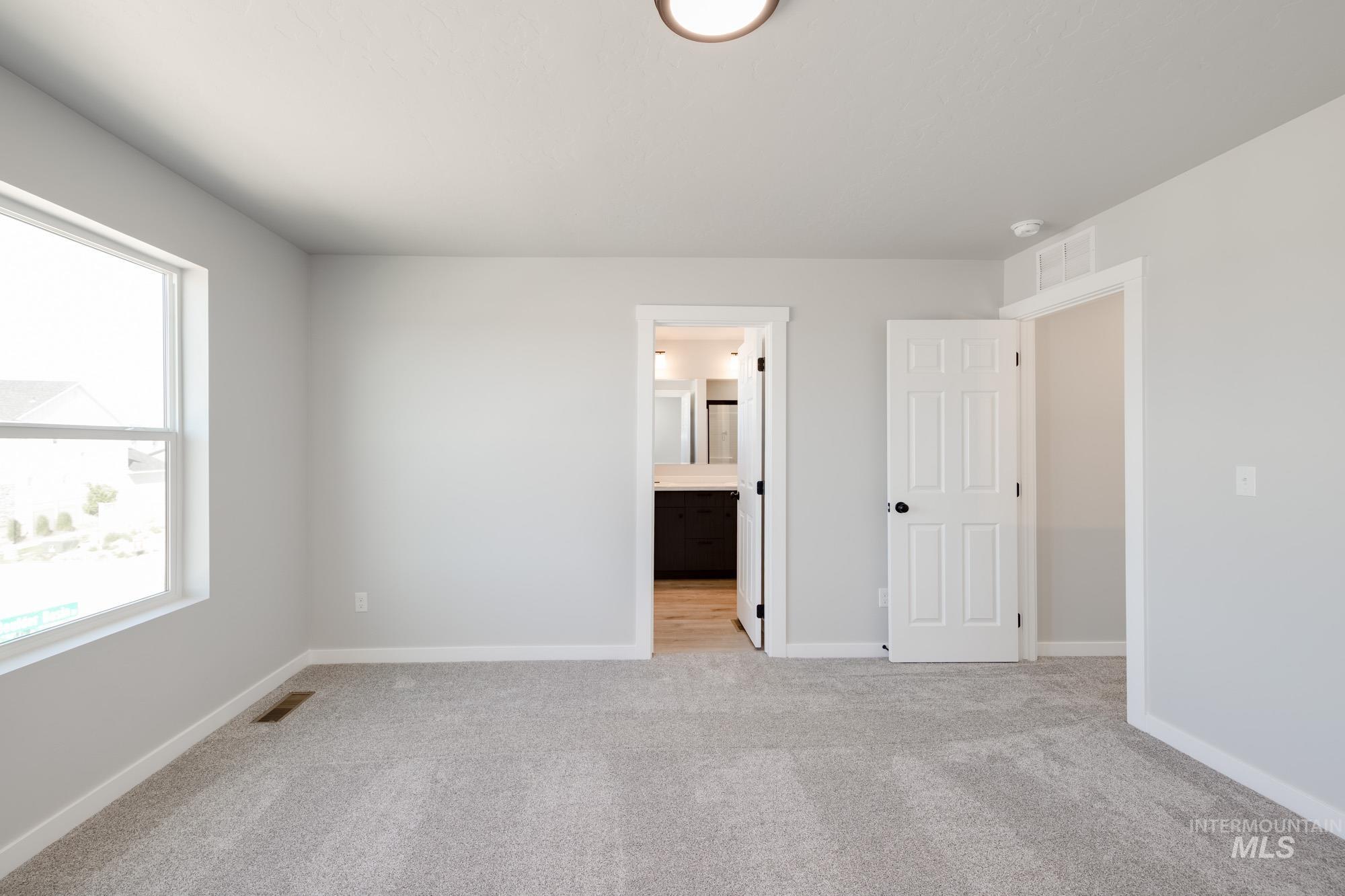 Unfurnished bedroom with light carpet and connected bathroom