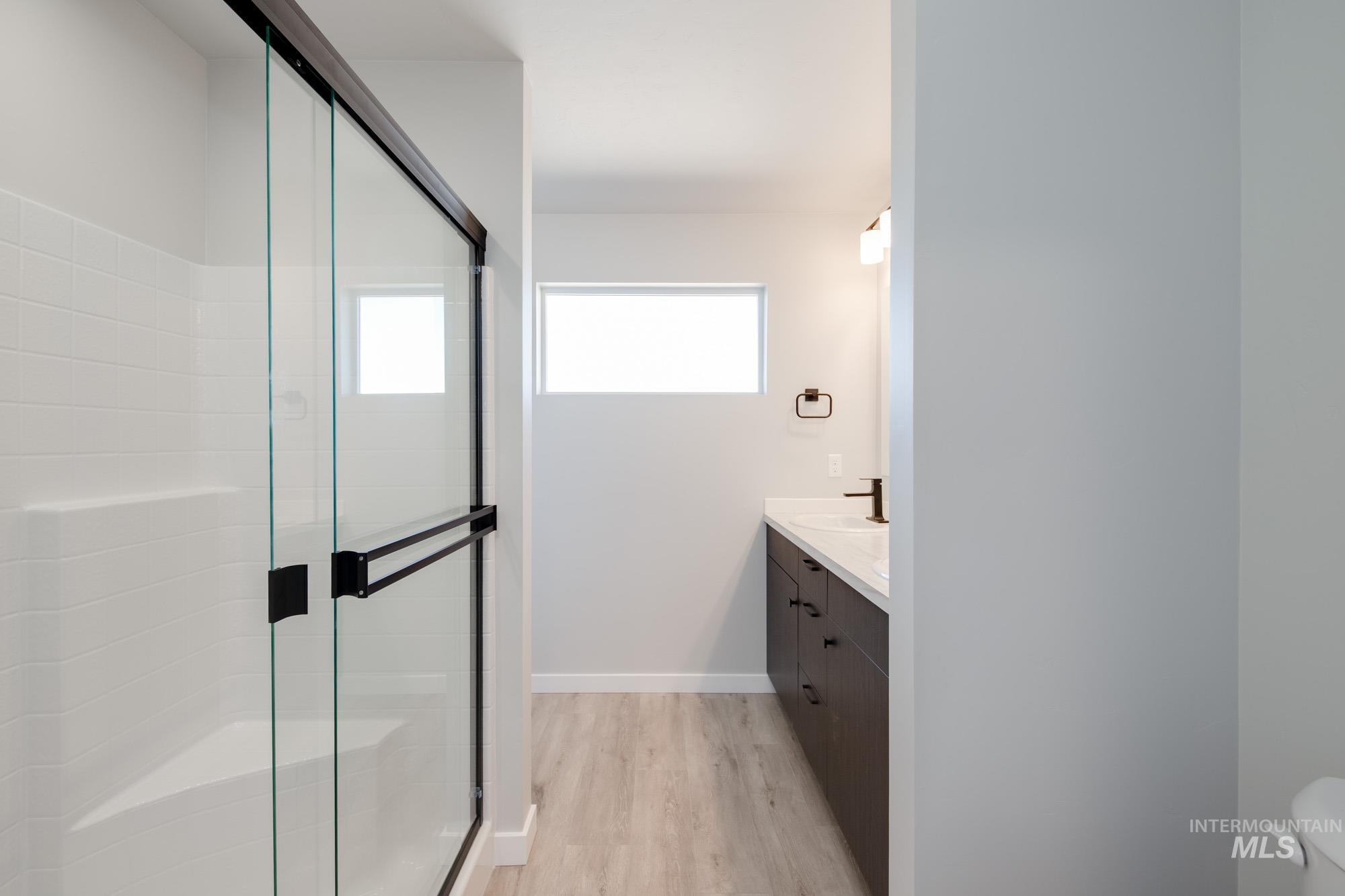 Bathroom featuring vanity, a shower stall, and light wood-style floors