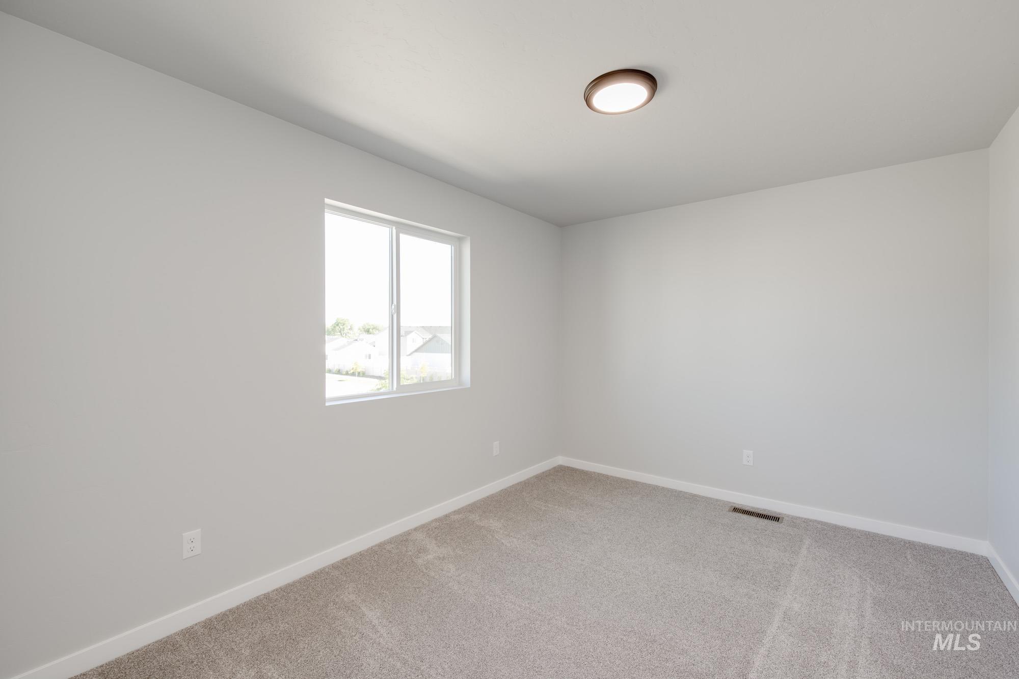Unfurnished room featuring baseboards and light carpet
